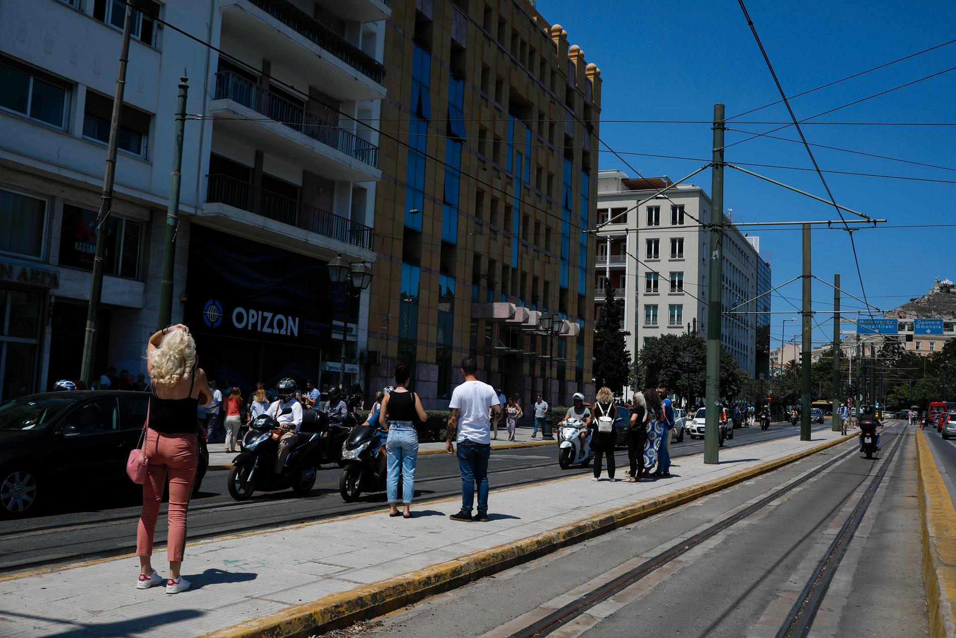 Människor på gatan utanför en byggnad i Aten efter fredagens skalv.