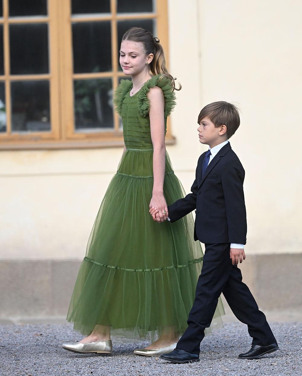 Prinsessan Estelle i en grön klänning från HM och prins Oscar i mörk kostym på kungens jubileumsfirande. 