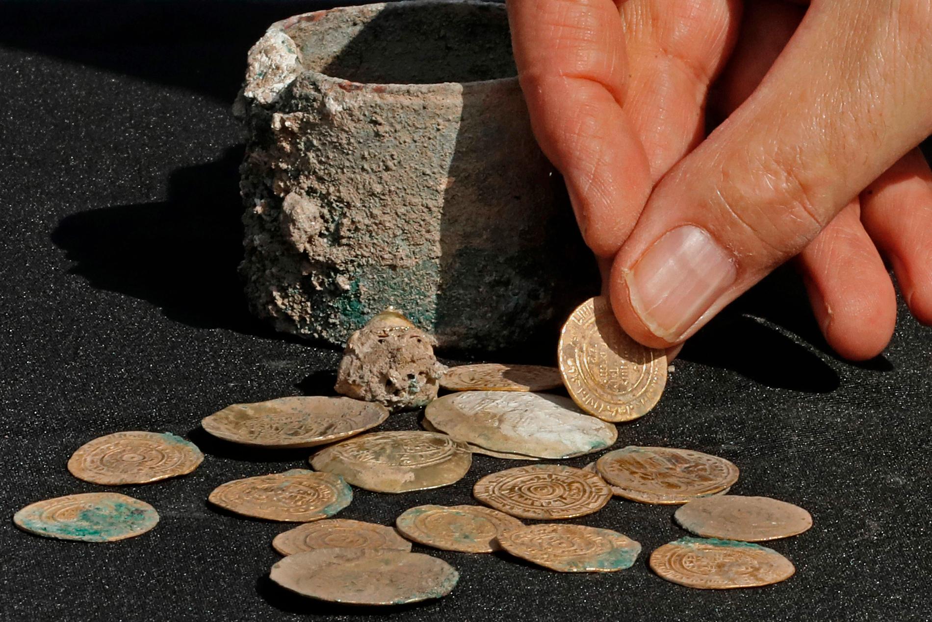 En skattgömma med 24 guldmynt och en öronring i guld har hittats i en liten bronskruka i ett gömställe i staden Caesarea i norra Israel.