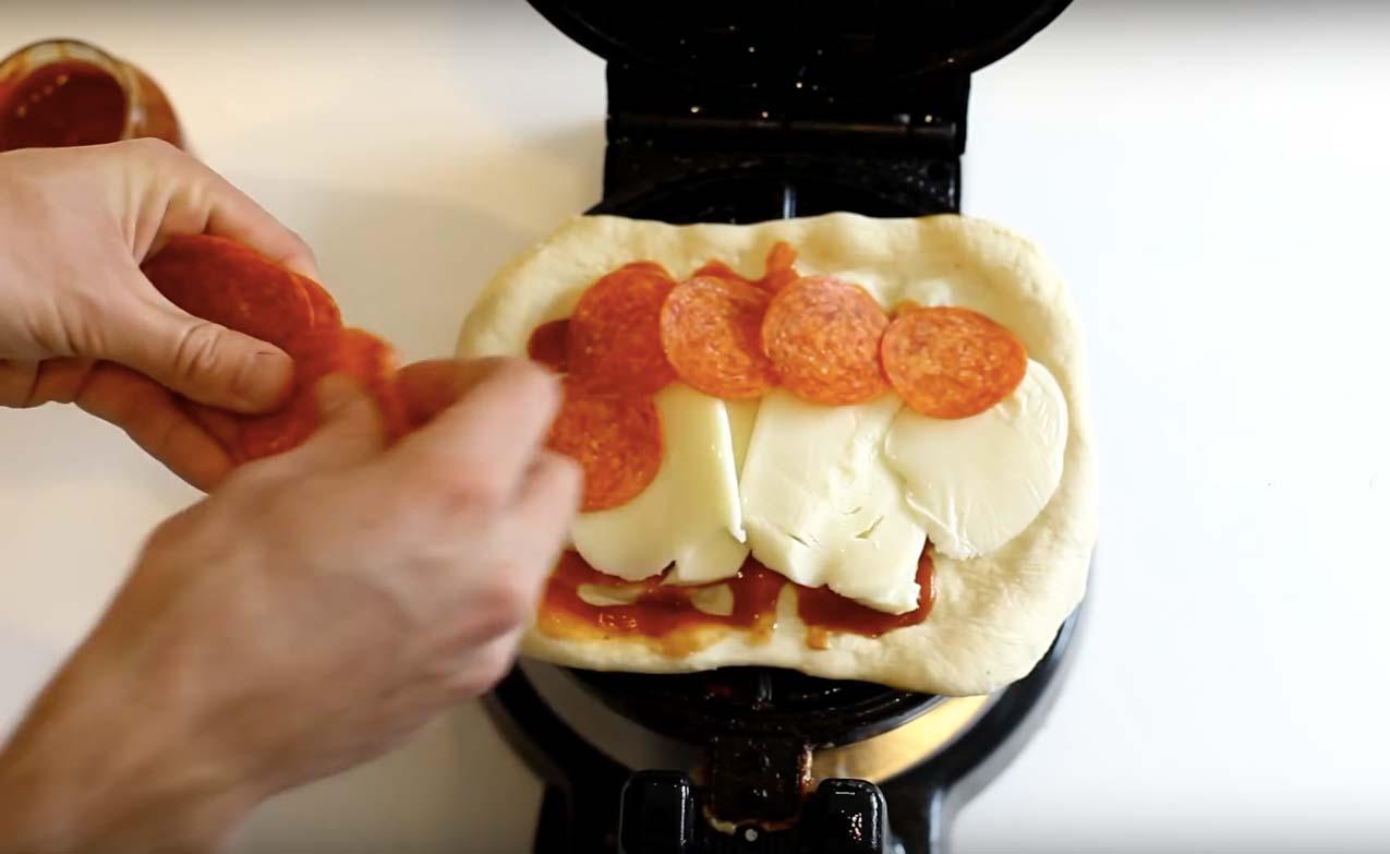 Fördela ut mozzarella och salami ovanpå lagret med tomatsås.