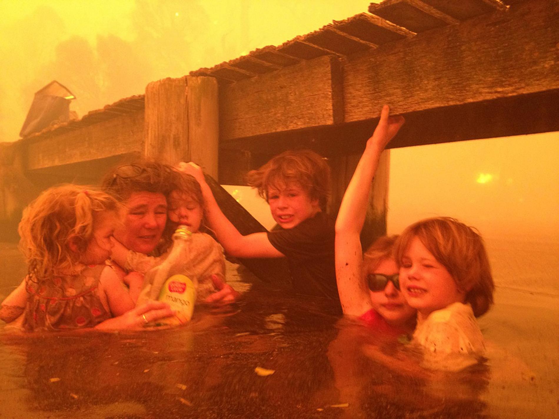 Tammy Holmes och hennes barnbarn, Charlotte, 2; Esther, 4; Liam 9; Matilda 11 och Caleb, 6 tar skydd under en brygga under en skogsbrand på Tasmanien 2013. Familjen tackade gud för att de alla överlevde.
