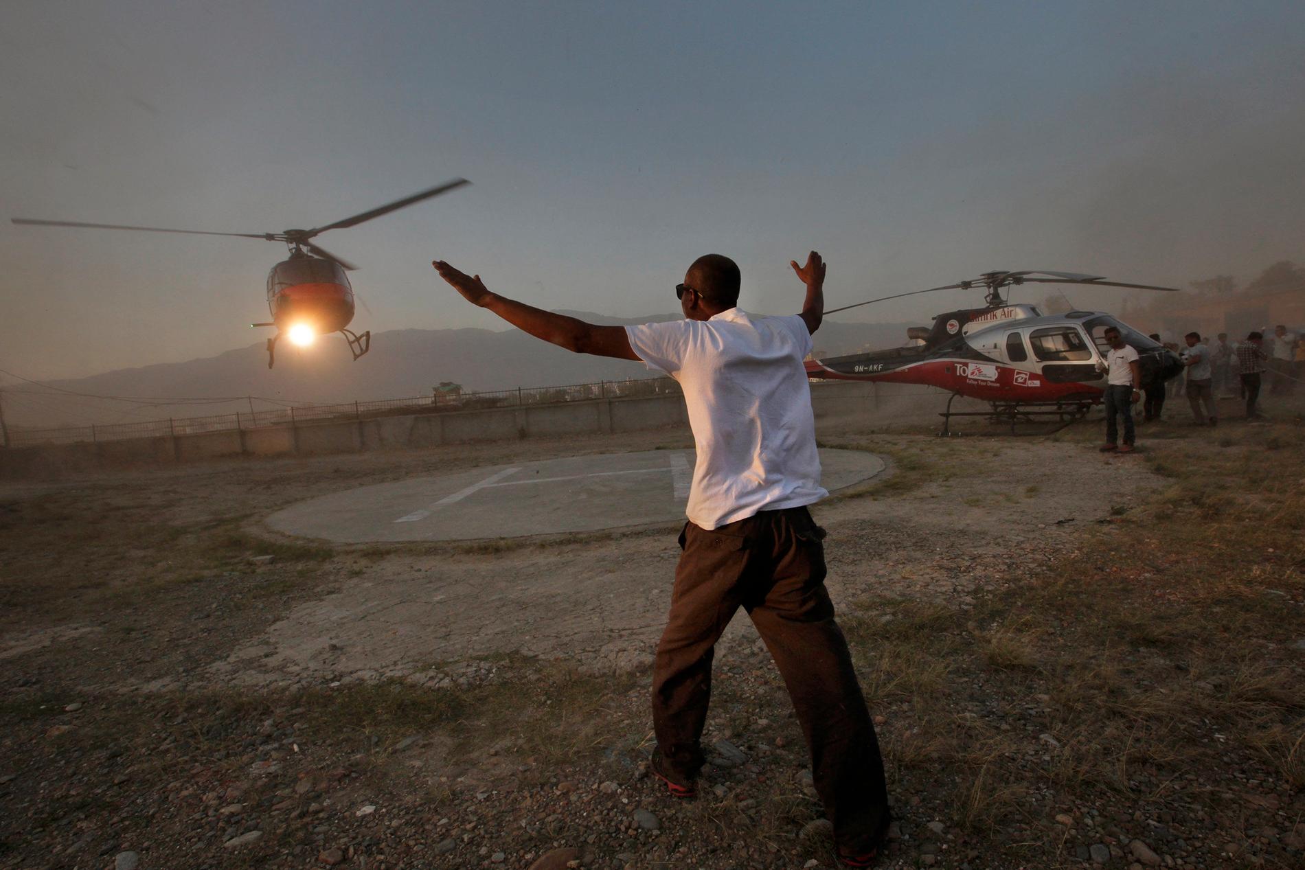Markpersonal visar vägen för en helikopter som ska landa i Katmandu i Nepal 2015.