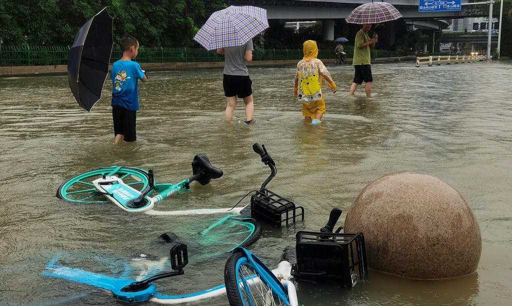 Invånare trampar genom översvämmade gator i staden Fazhou i efterdyningarna av Tyfonen Doksuri.