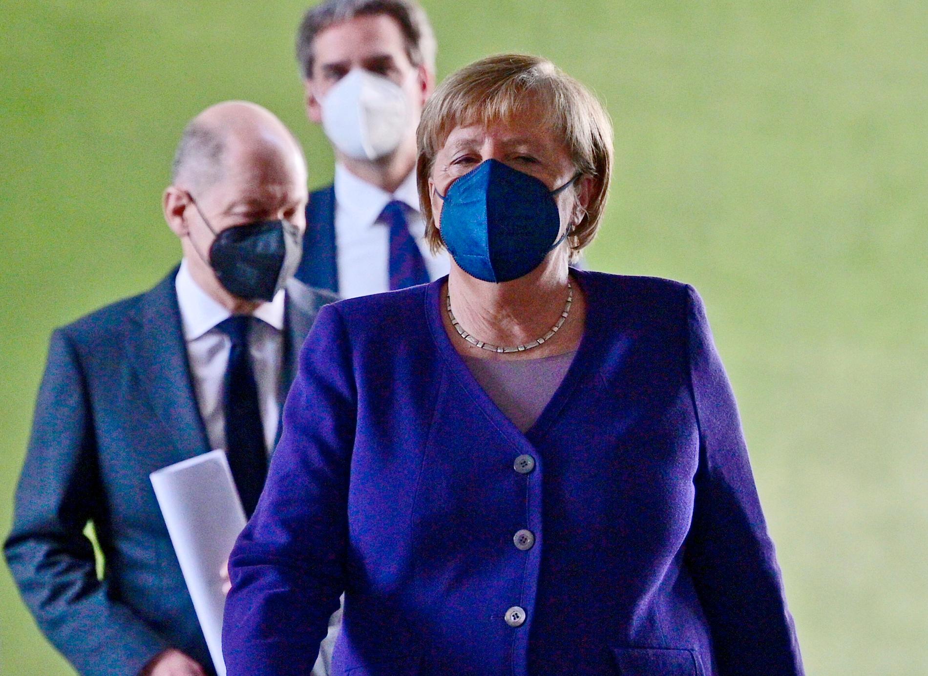 Tysklands avgående förbundskansler Angela Merkel, med tillträdande förbundskansler Olaf Scholz strax bakom, har i samråd med förbundsländernas ledare beslutat att skärpa kraven om vaccinering.