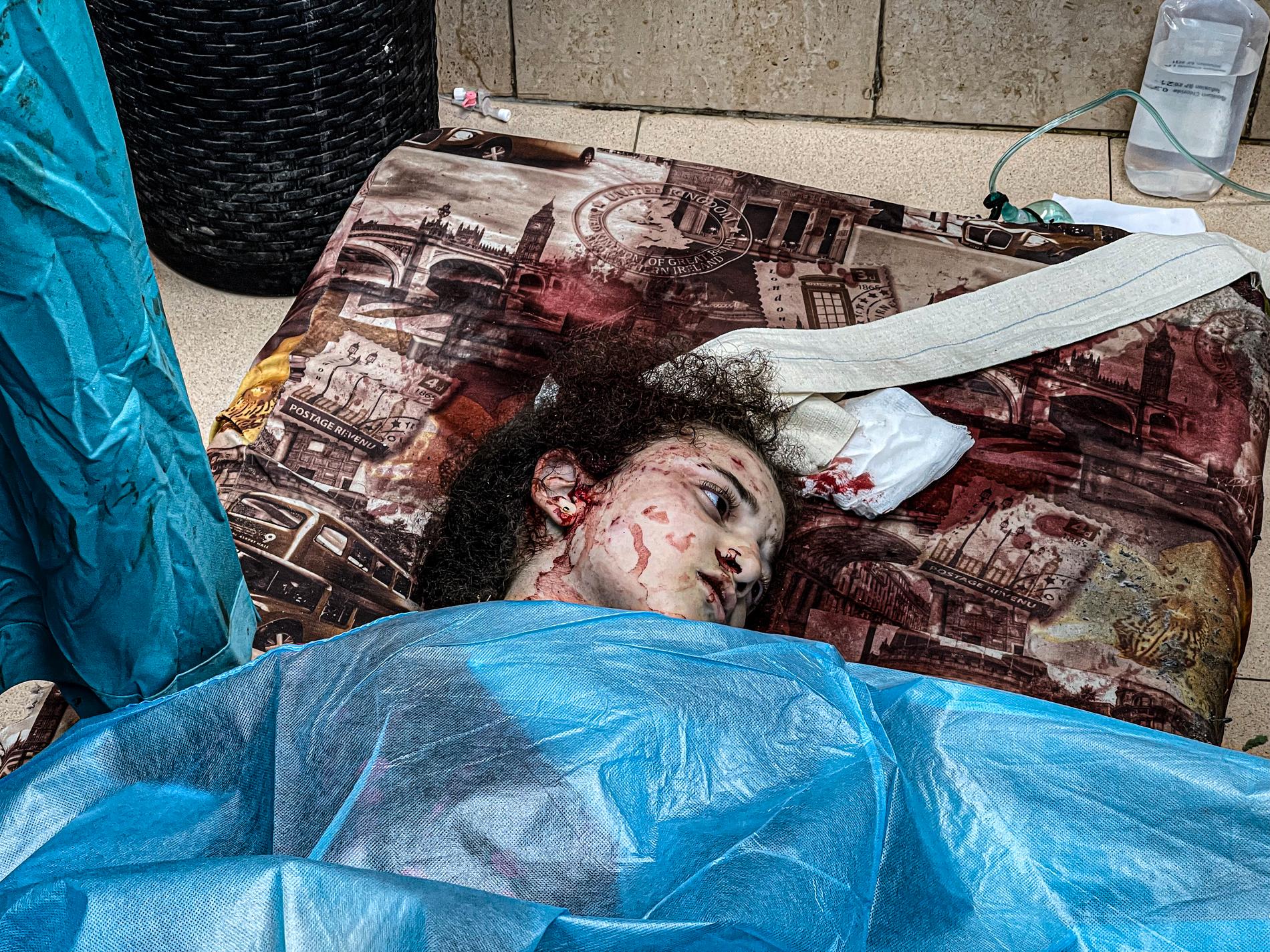 14-åriga Raghad Ahmed har fått en madrass på golvet, mitt i kaoset på sjukhuset i centrala Gaza. 