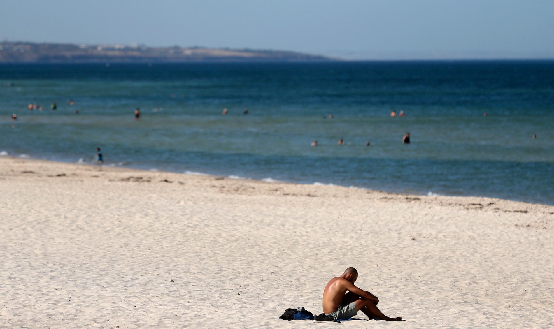 En man försöker svalka sig på stranden i Adelaide i Australien. Staden fick 47 grader på torsdagen, vilket var den högst uppmätta temperaturen på över 80 år.