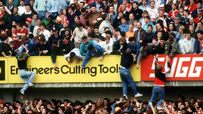 En bild från Hillsborough-katastrofen 1989. Supportrar flyr trängseln och får hjälp av fans på en övre sektion.