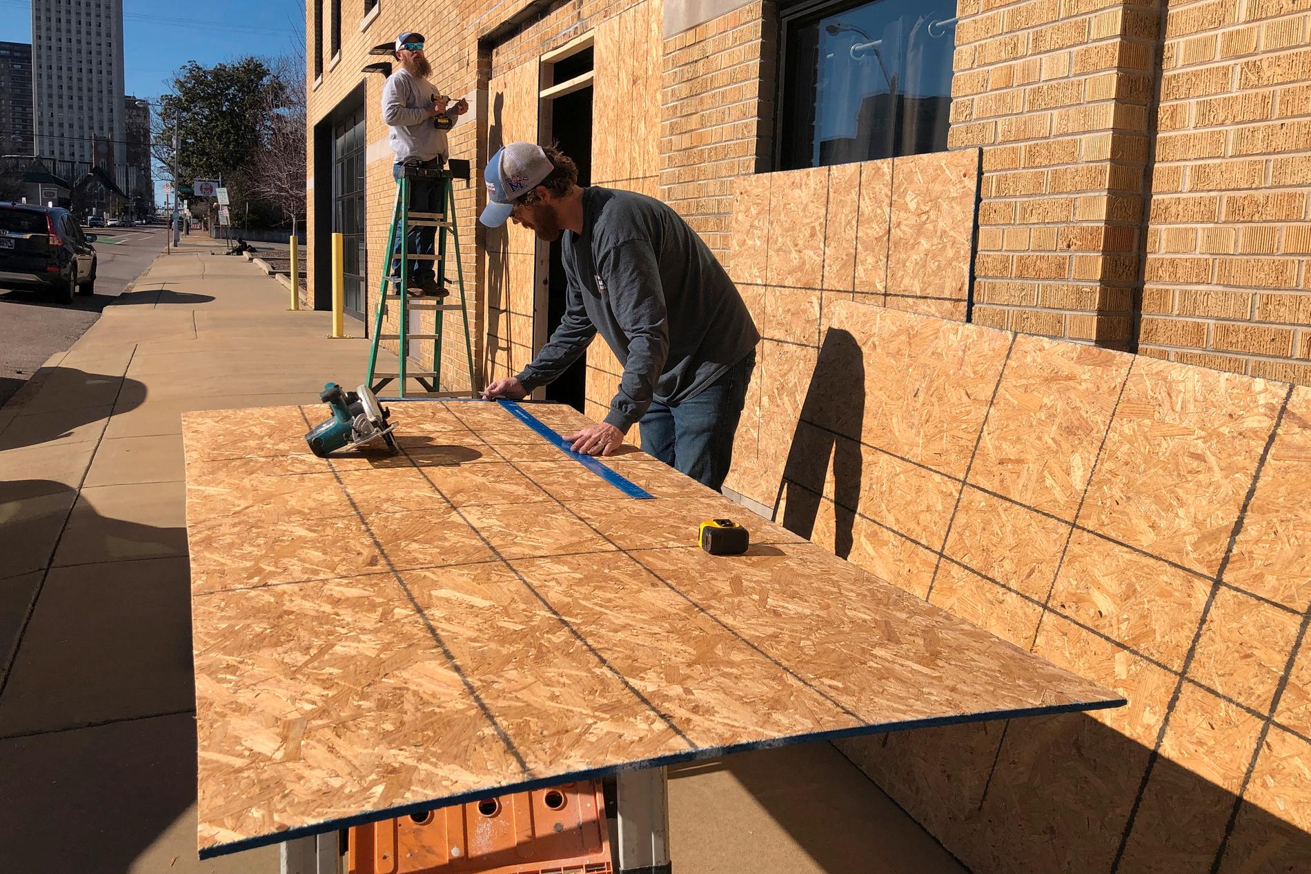 Ryan Kellum och Ricky Noe förbereder plywoodskivor som skydd för fönstren på sitt jobb inför de kravaller som tros följa när videon har släppts.