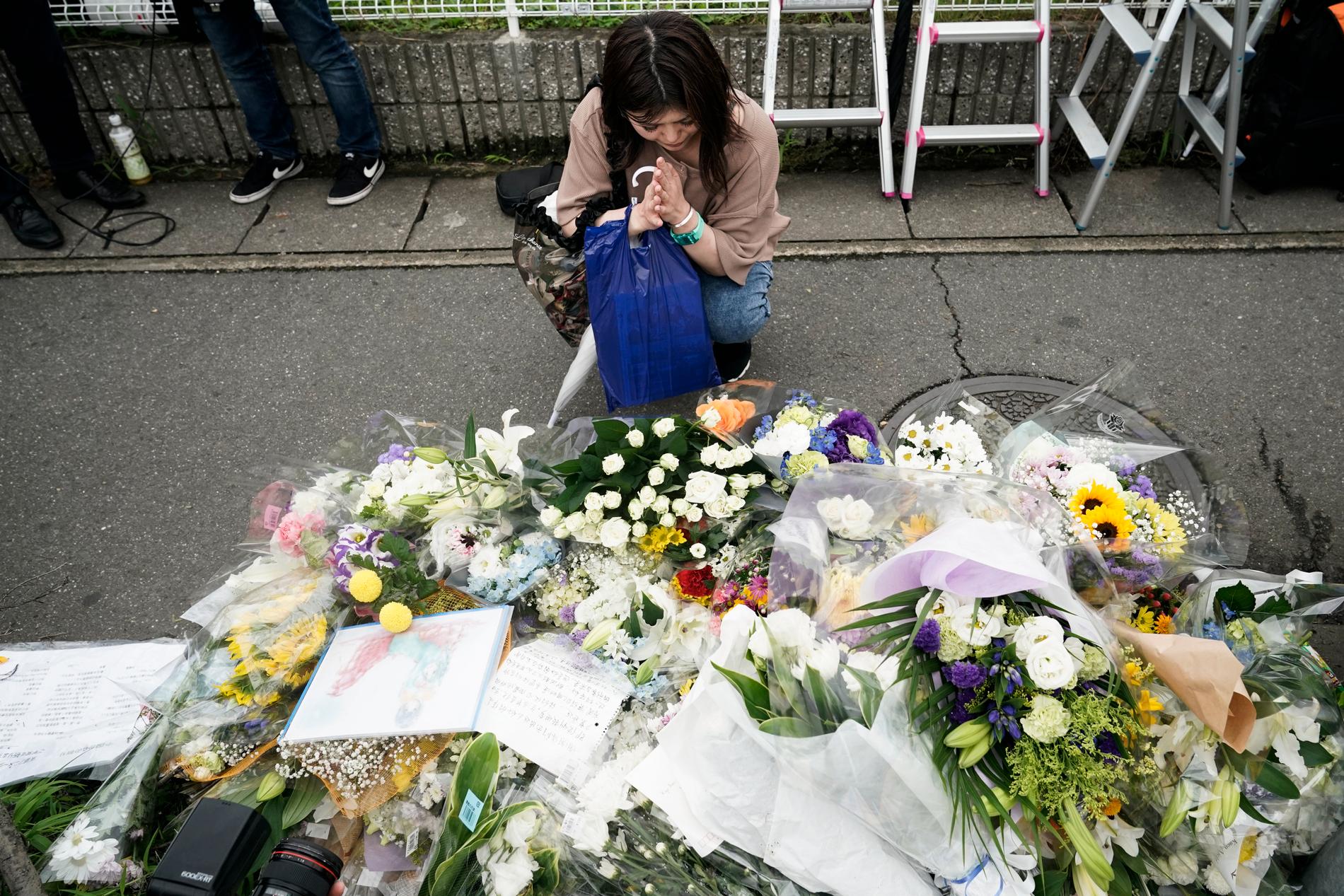 En kvinna ber för offren vid animationsstudion Kyoto Animation dagen efter den förödande branden.