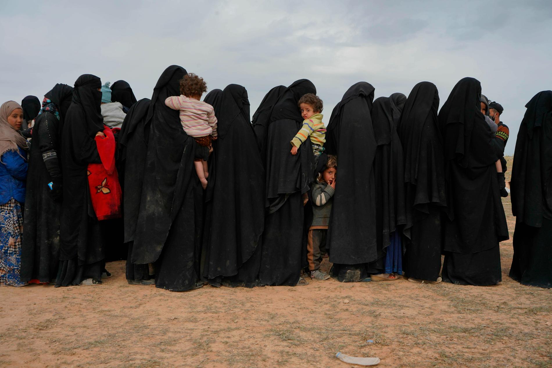 Kvinnor och barn väntar framför en kontroll vid samlingsplatsen för de människor som senast evakuerats ur IS sista fäste i Syrien.