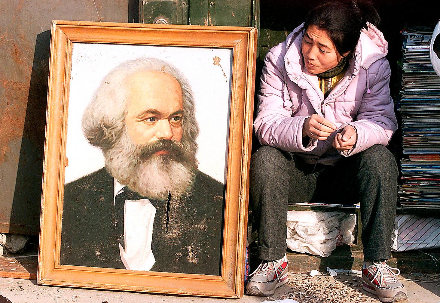 Kinesisk kvinna med ett porträtt av Karl Marx, den tyske ekonomen och filosofen som bland annat skrev Kommunistiska manifestet tillsammans med Friedrich Engels. Lördag 5 maj 2018 är det 200 år sedan Marx föddes. 