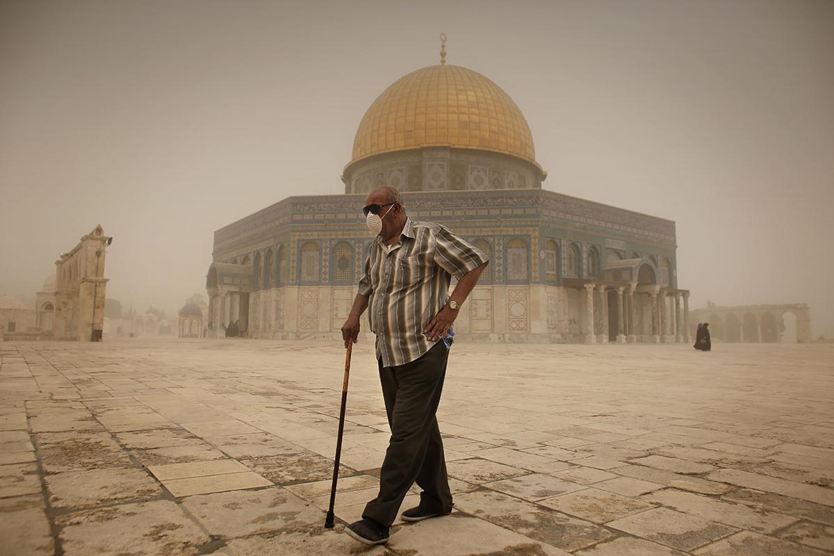En palestinsk man har skyddat sig mot sandstormen med solglasögon och munskydd i Jerusalem.