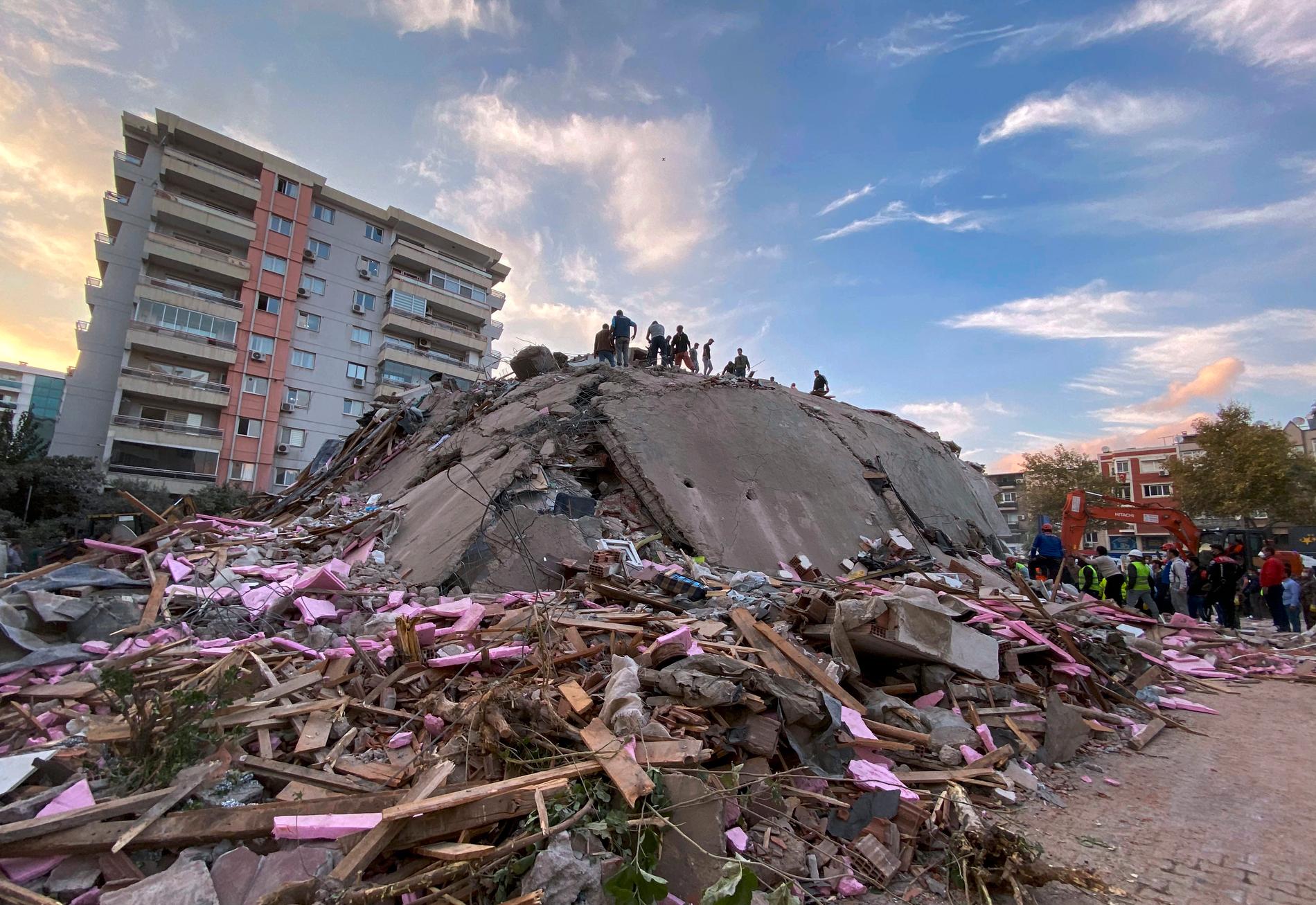 Räddningsarbetare letar efter överlevande i rasmassorna efter en byggnad som kollapsade i staden Izmir i Turkiet.