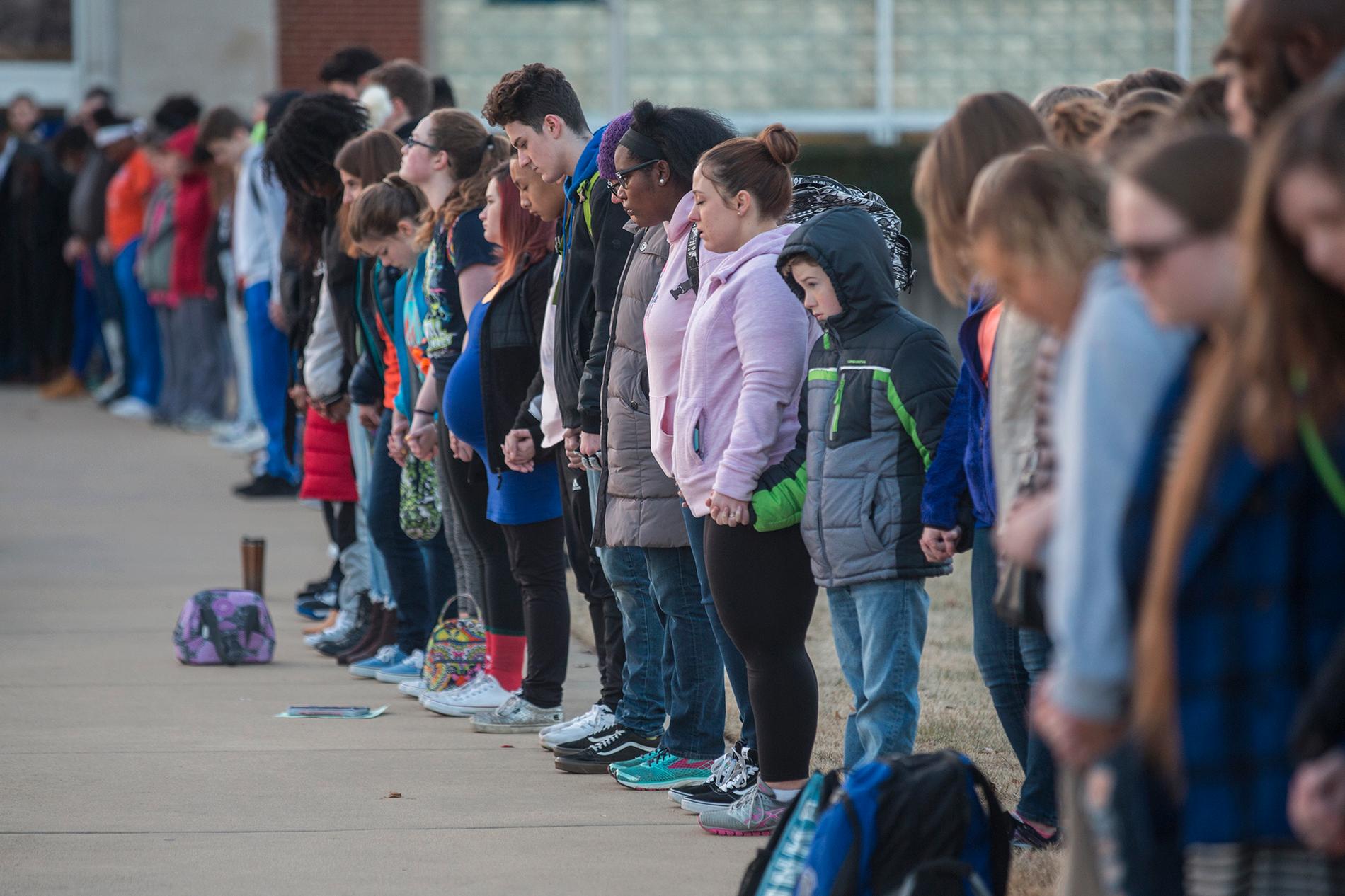 Studenter och boende vid en skola i Paducah i Kentucky håller varandras händer efter att två 15-åringar skjutits till döds och minst tolv skadats på en annan skola, Marshall County High School, i delstaten i januari.