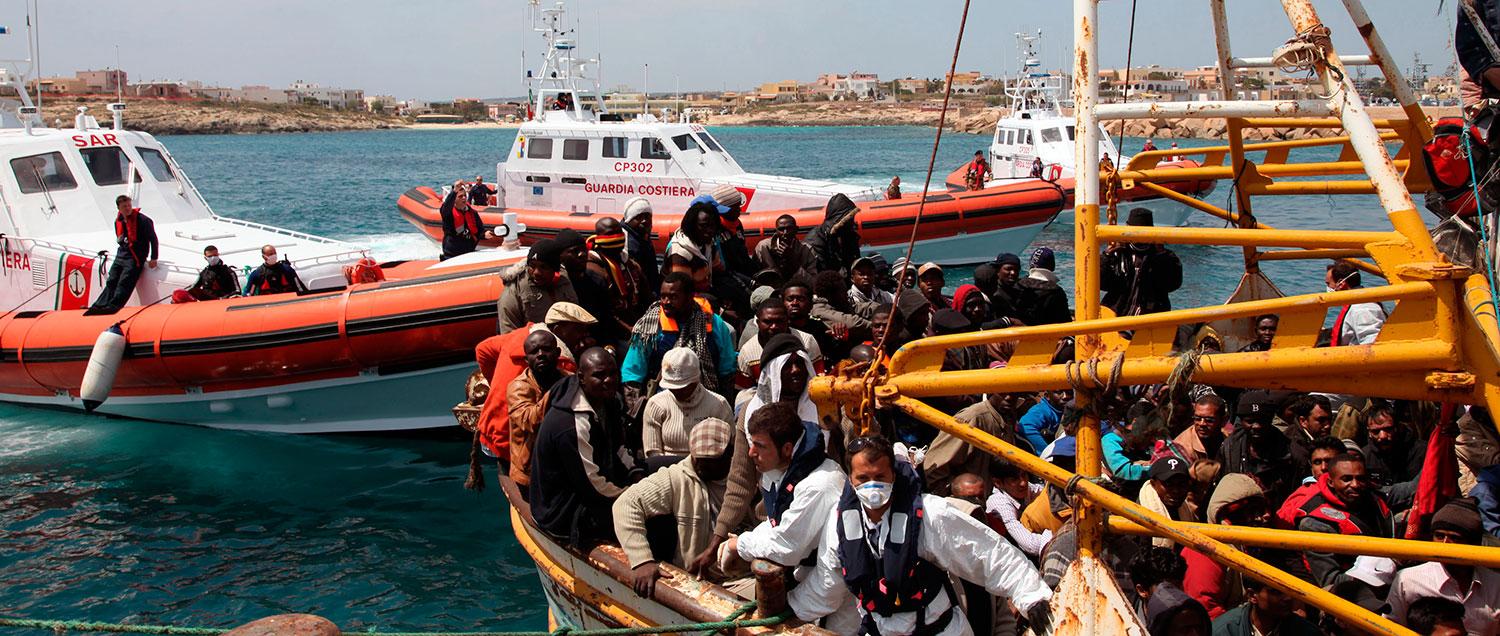 Ett fartyg med hundratals flyktingar anländer till hamnen på ön Lampedusa i Italien.