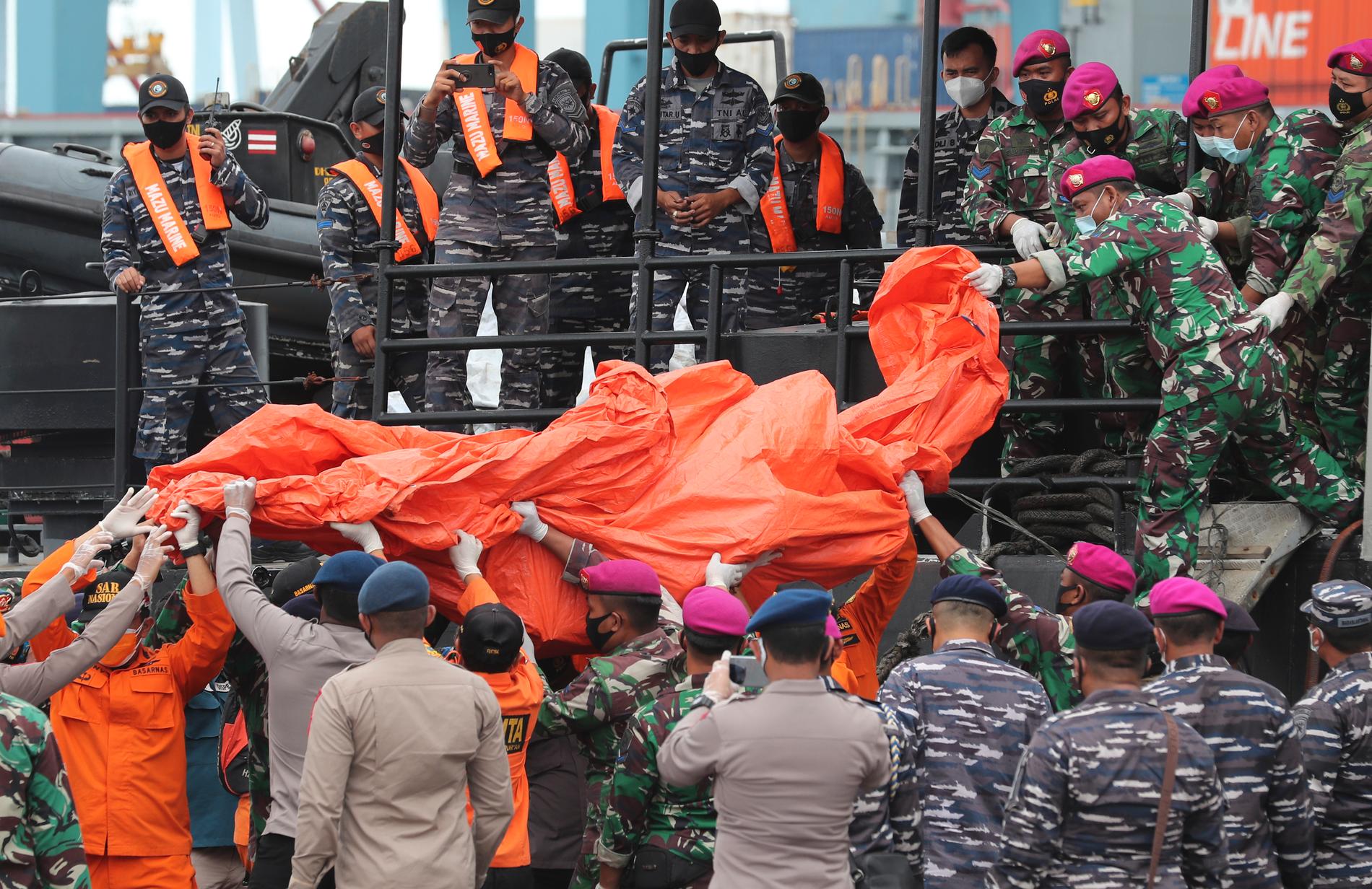 Indonesiska flottan och polis tar omhand föremål som tros vara från det försvunna flygplanet.