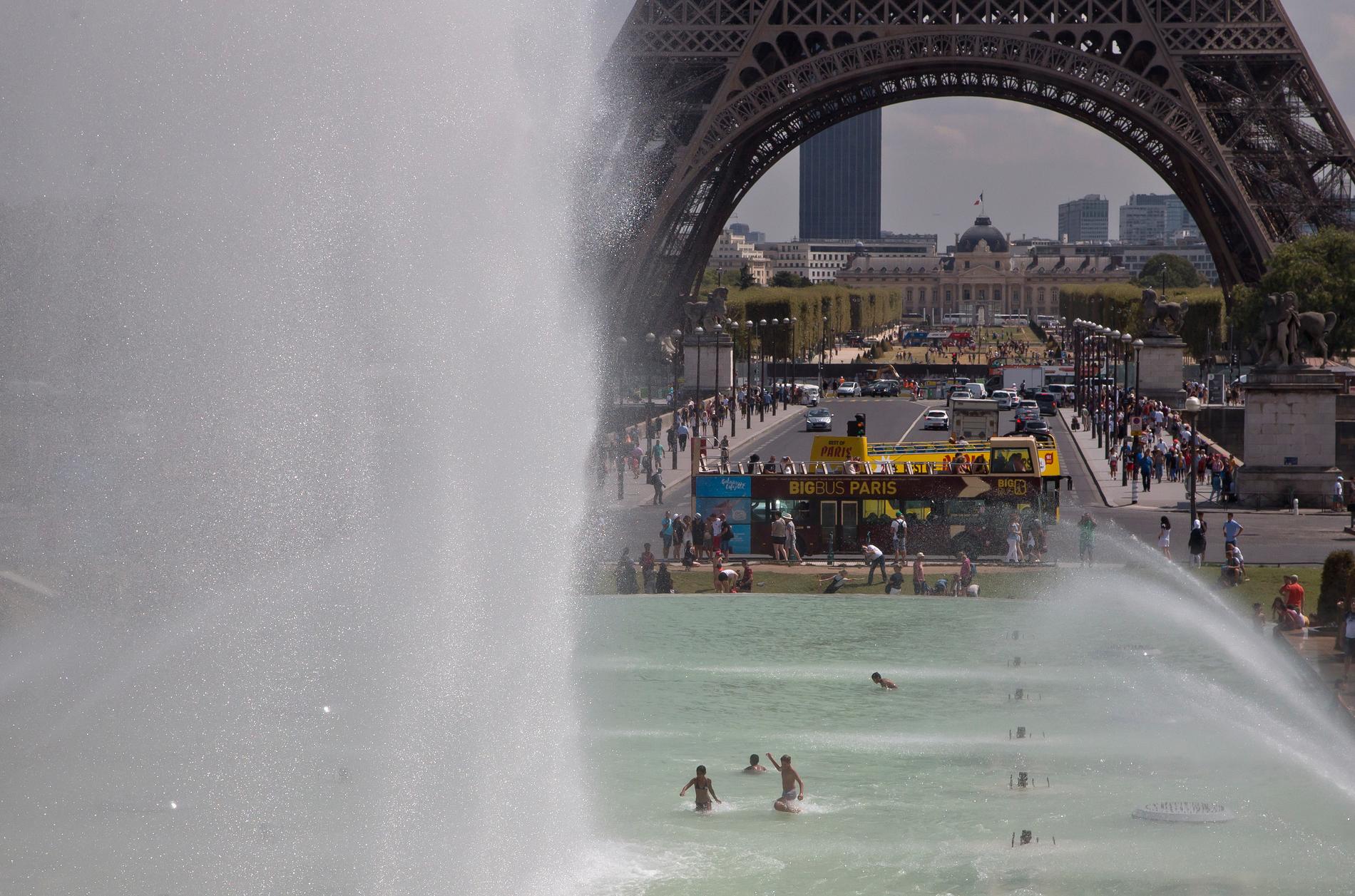Barn svalkar sig i en fontän nära Eiffeltornet, där en dispyt om kösystem på onsdagen fick personalen att gå ut i strejk.