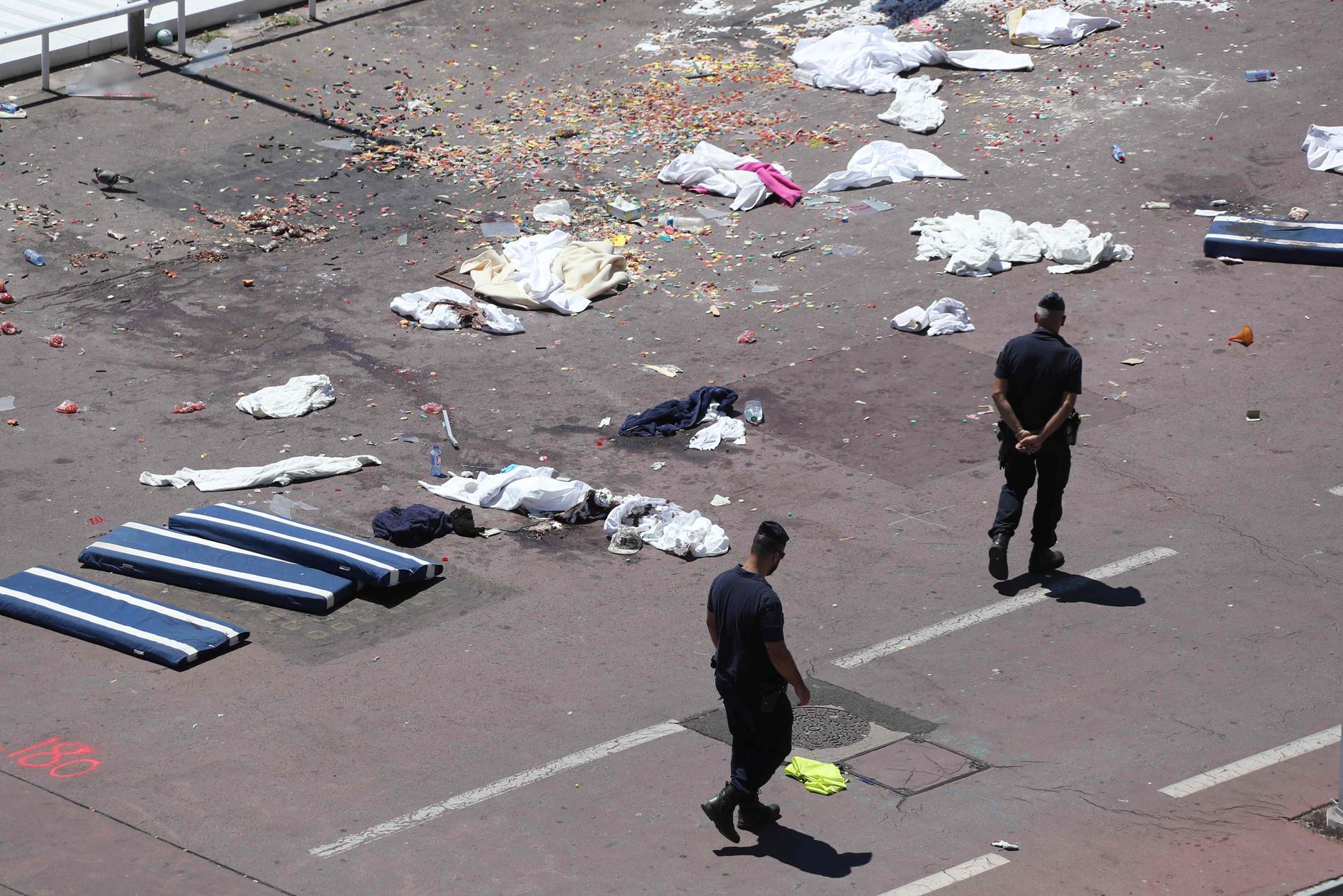 Polismän går på fredagen förbi kläder och madrasser vid platsen för terrorattacken.