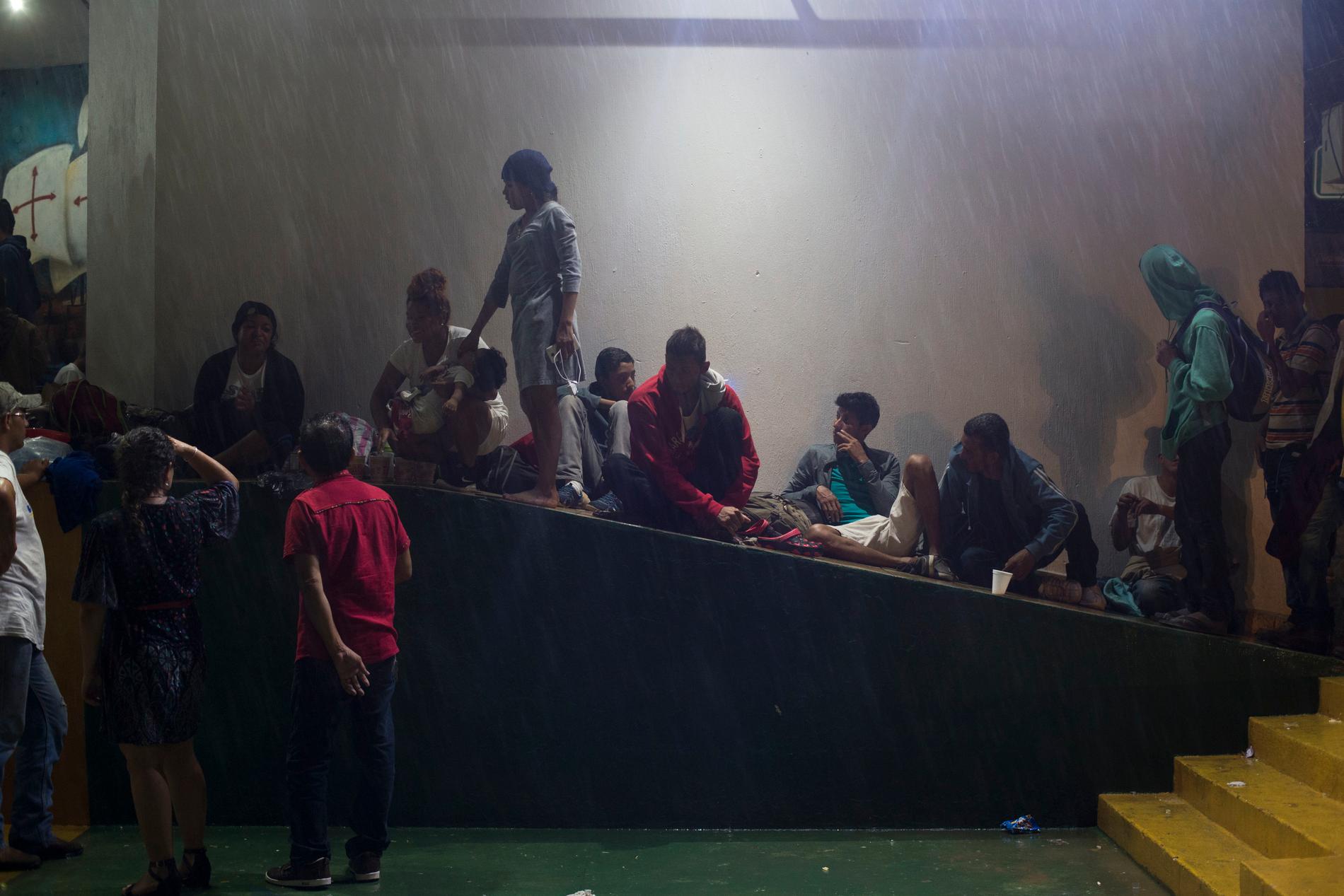 En grupp migranter som anlänt till Tecun Uman, vid gränsen mellan Guatemala och Mexiko, tar skydd från regnet sent på torsdagen.