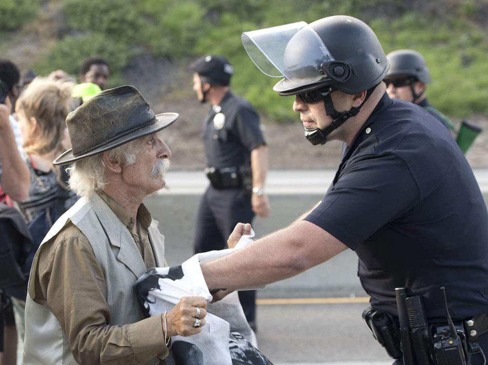 Polisen hindrar en demonstrerande man från att gå över en motorväg i Los Angeles. Den stora folkmassan som samlats för att uttrycka sitt missnöje över den friande domen hade strax innan gett sig ut på motorvägen och stoppat trafiken.