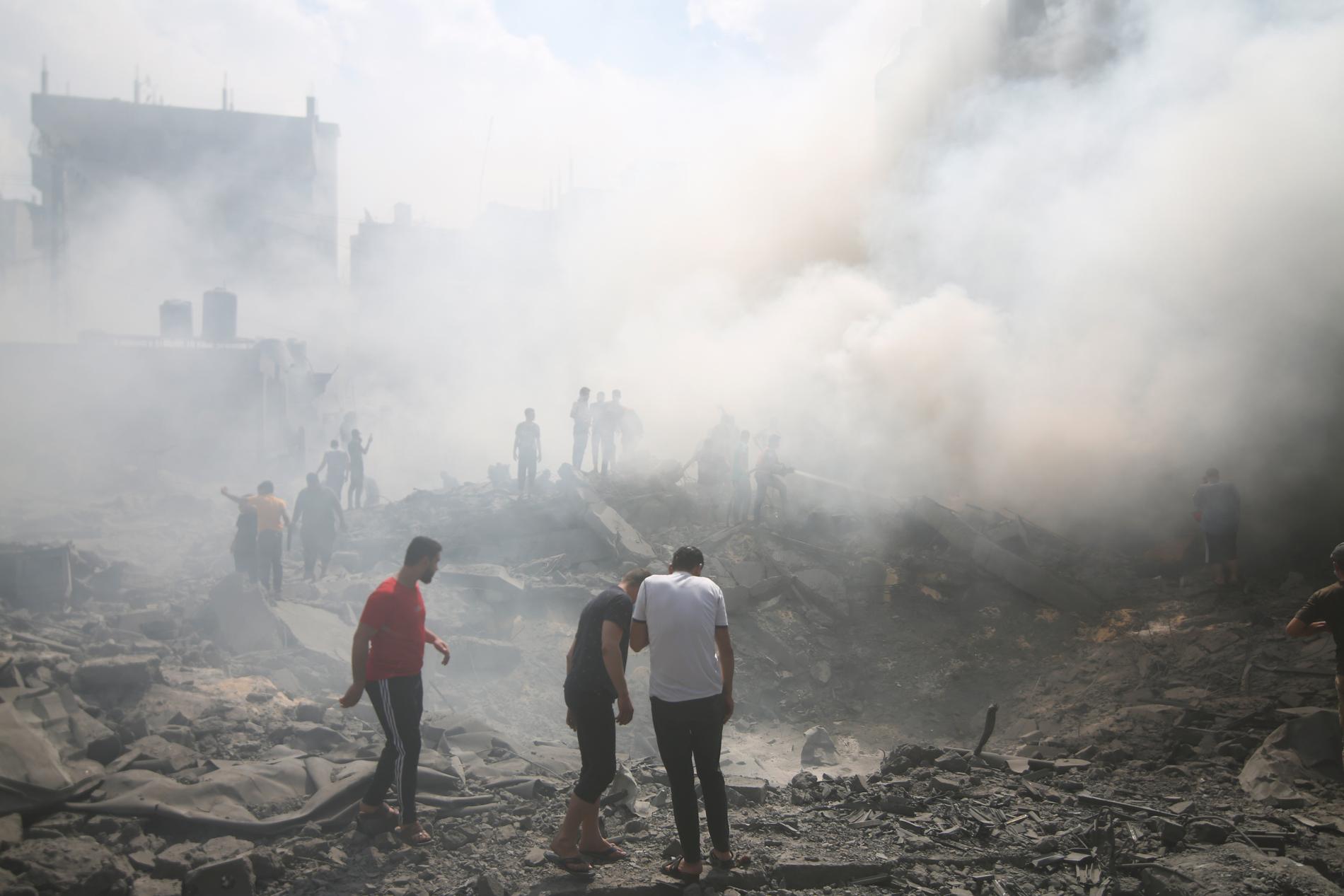 Några män letar efter överlevande i ruinerna efter ett israeliskt luftangrepp i Rafah.