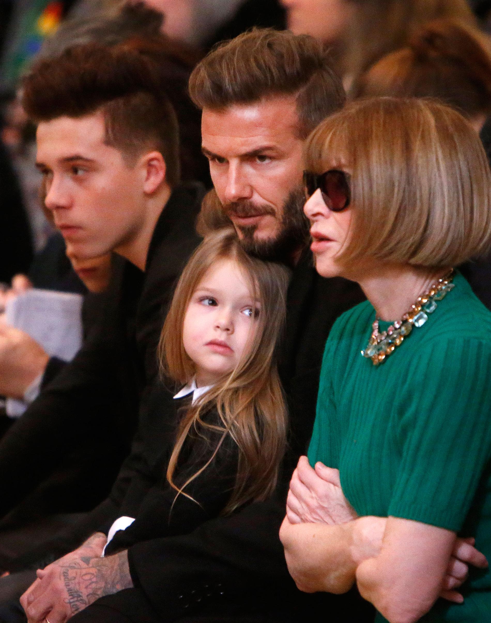 David Beckham med dottern Harper i knäet och sonen Brooklyn (till vänster).