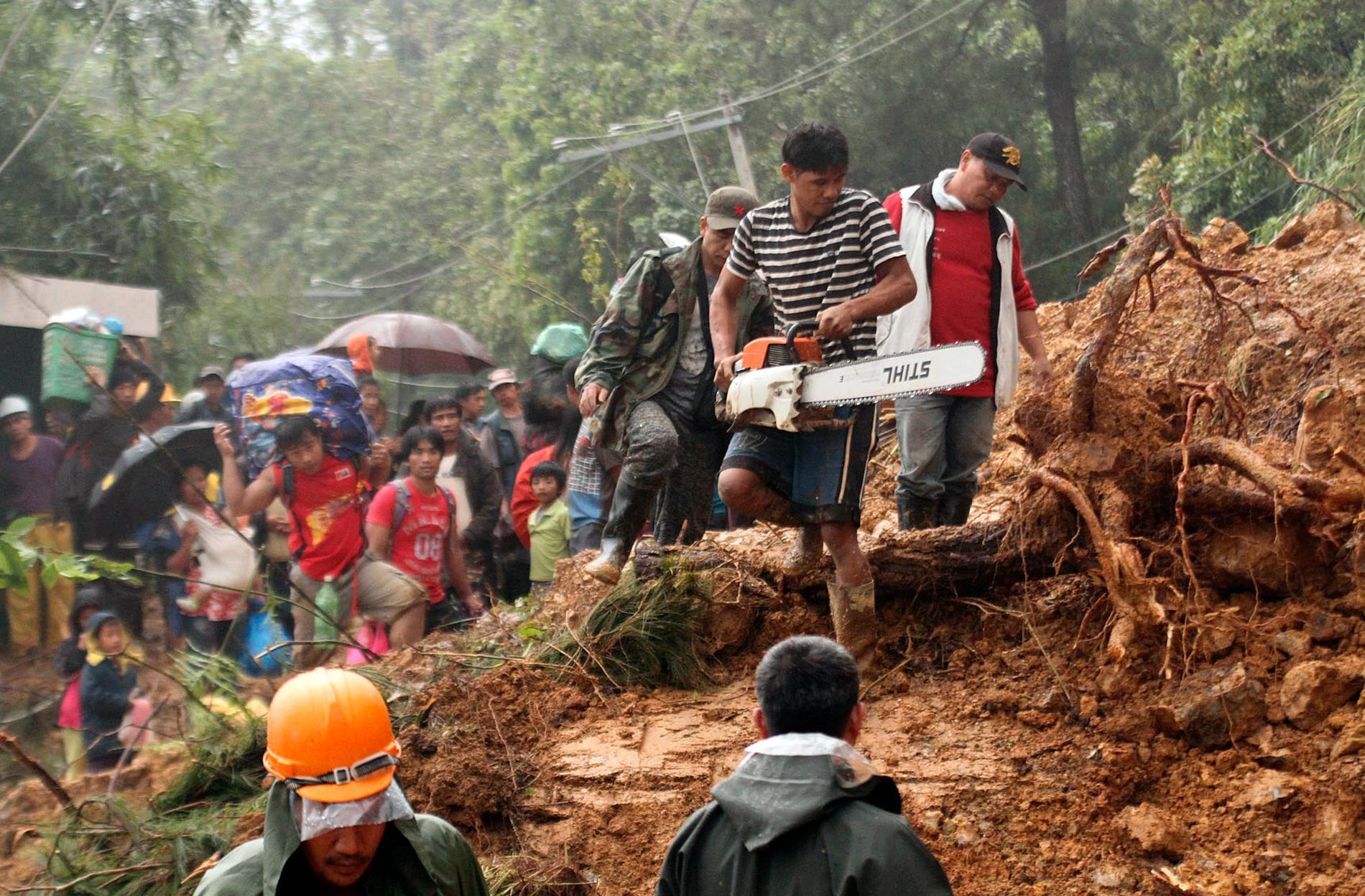 Invånare i Itogon i Filippinerna evakueras från ett område som drabbats av ett skred.