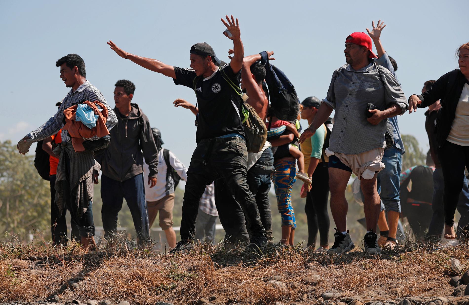 Centralamerikanska migranter som lyckats ta sig över gränsfloden Suchiate när de ser mexikanska nationalgardet närma sig.