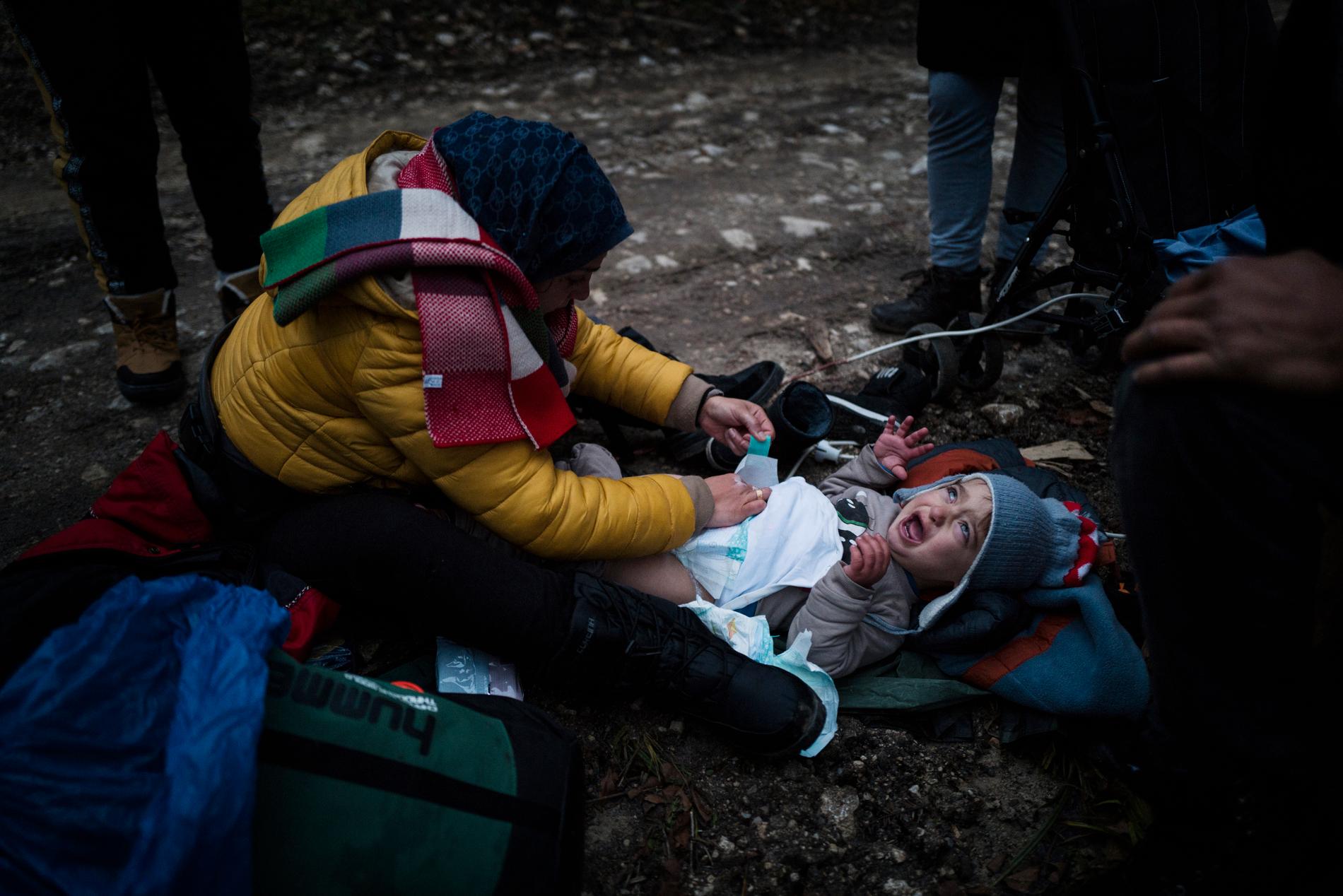 24-åriga Fatim byter blöjor på sin son Omar 1,5 innan de fortsätter sin vandring mot gränsen till Kroatien. 