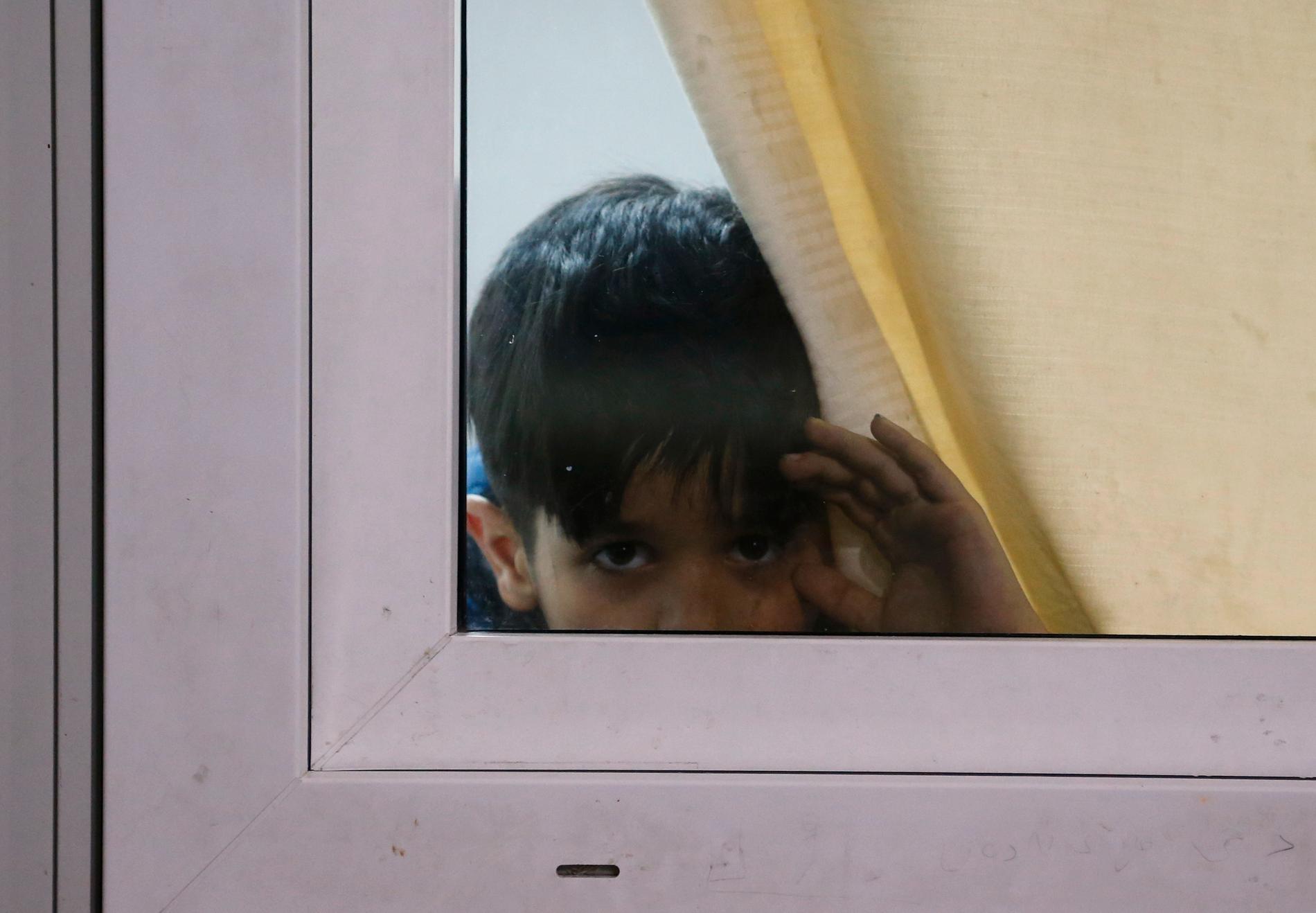 En pojke tittar ut genom ett fönster på ett förvar för asylsökande och migranter i Bihac i Bosnien-Hercegovina. Arkivfoto.