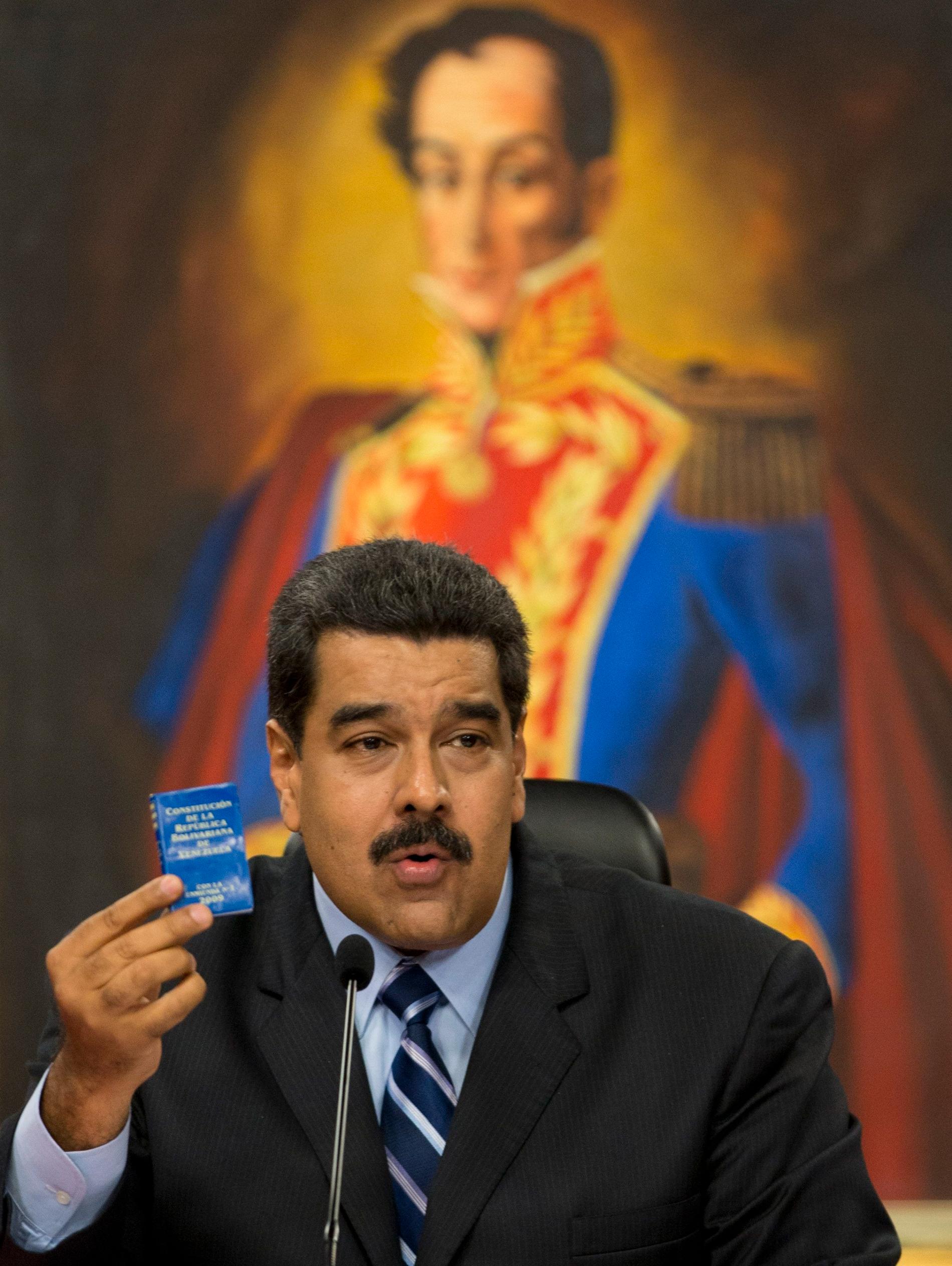 Nicolas Maduro håller i en bok med den venezolanska konstitutionen.