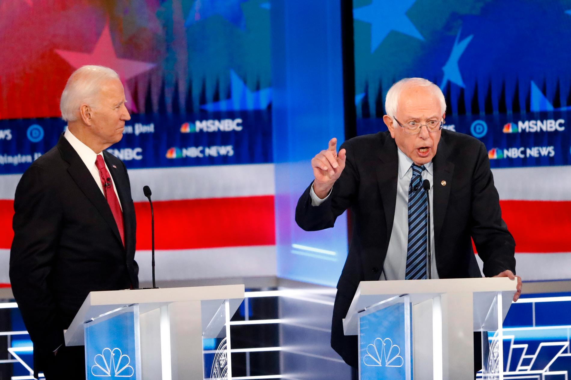 Den demokratiske tidigare vicepresidenten Joe Biden lyssnar på Vermontsenatorn Bernie Sanders vid en tidigare debatt.