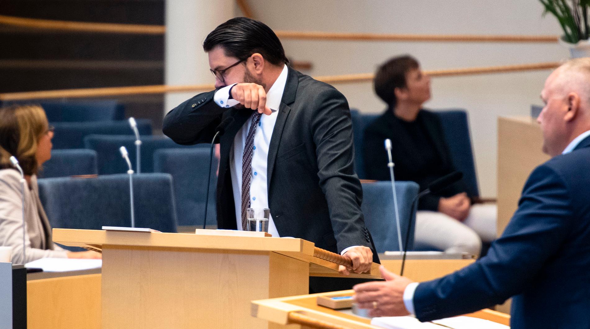Sverigedemokraternas partiledare Jimmie Åkesson (SD) var förkyld vid riksdagsårets första partiledardebatt i riksdagen 2020. Om han har tagit coronavaccinet idag är fortfarande oklart.