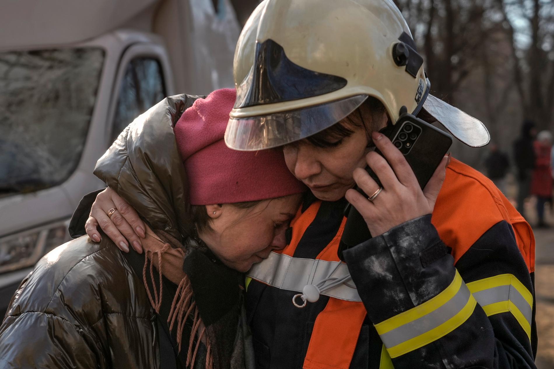 En räddningsarbetare tröstar en kvinna utanför ett förstört bostadshus i Kiev i tisdags.