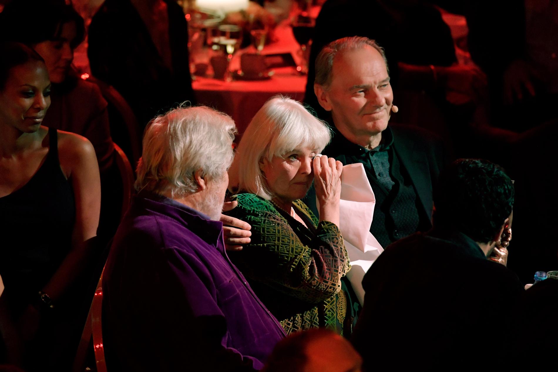 En märkbart tagen Anita lyssnade på Mikael Wiehes sång mellan Sven Wollter och Björn Granath.