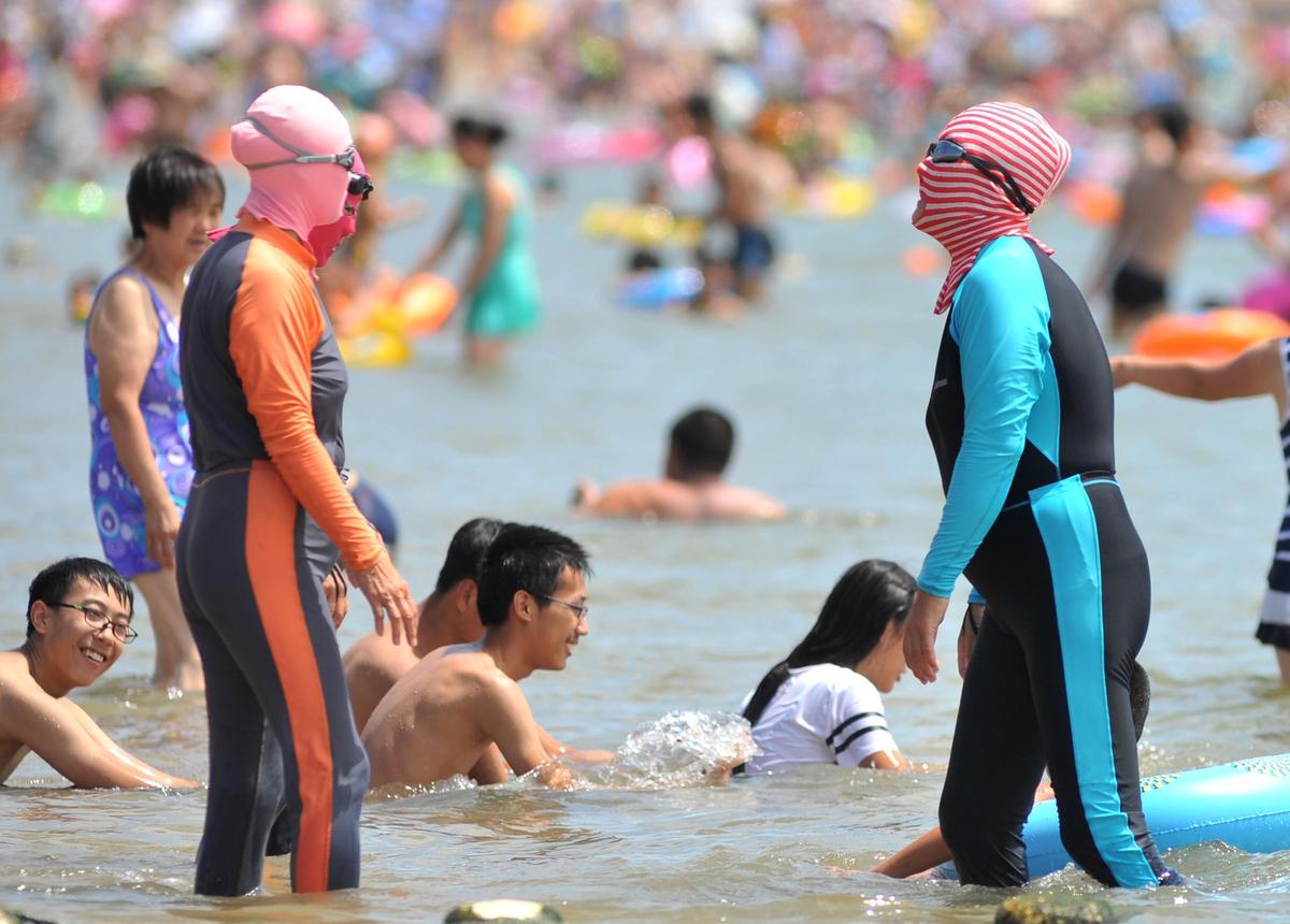 Allt fler kineser använder heltäckande skydd, som facekini, för att skydda sig från solen i värmeböljan.