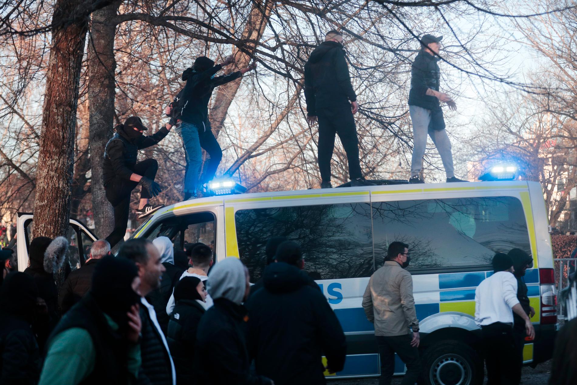 Motdemonstranter klättrar upp på en polisbuss i Sveaparken i Örebro.