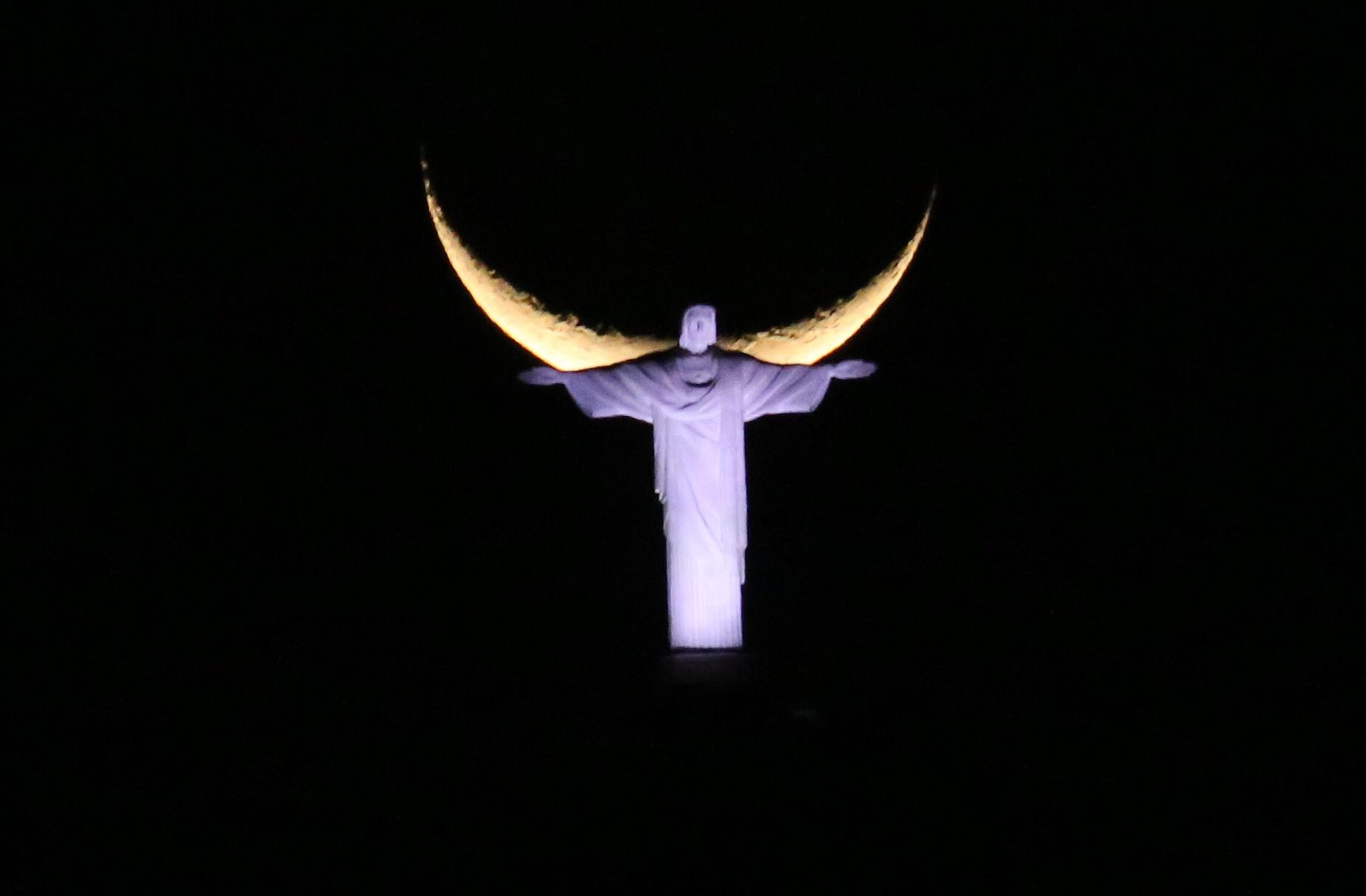 Nymånen ger vingar åt Kristusstatyn i Rio de Janeiro, Brasilien på torsdagskvällen.