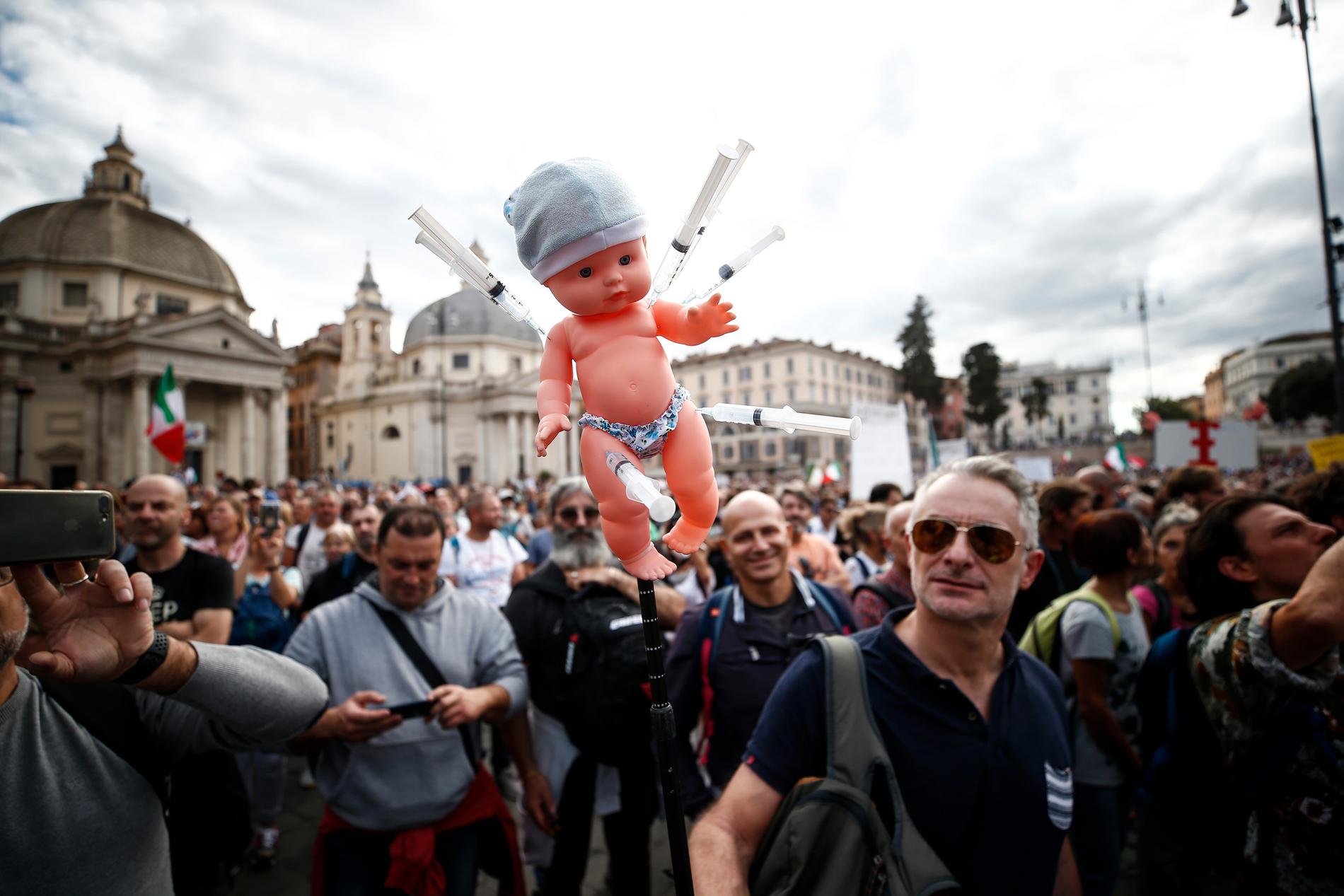 En docka med sprutor vid en protest i huvudstaden Rom mot vaccinpassen. Bilden är tagen i lördags.