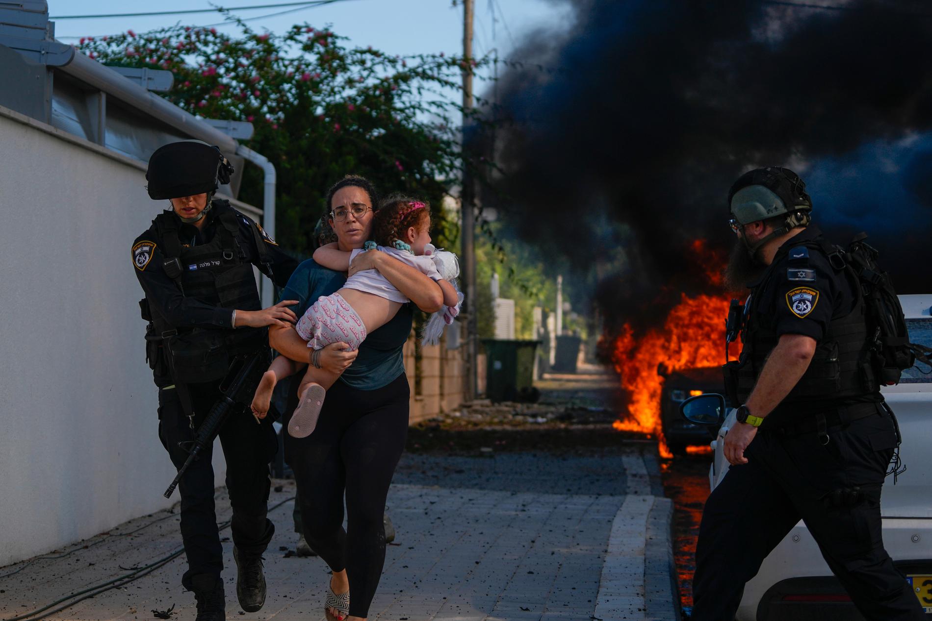 Poliser evakuerar en kvinna med hennes barn efter att en raket slagit ner i Ashkelon.