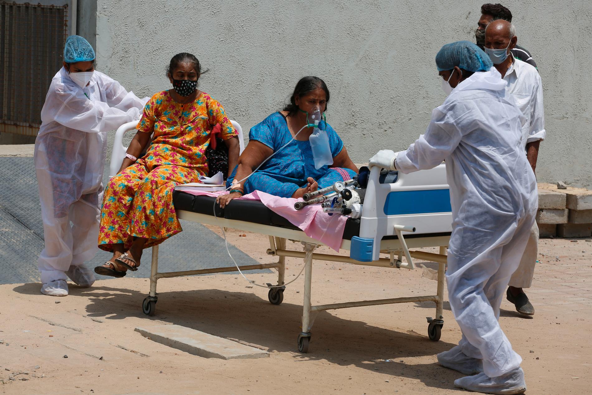 Vårdpersonal flyttar covidpatienter från ett sjukhus till ett annat i Ahmedabad i Indien.