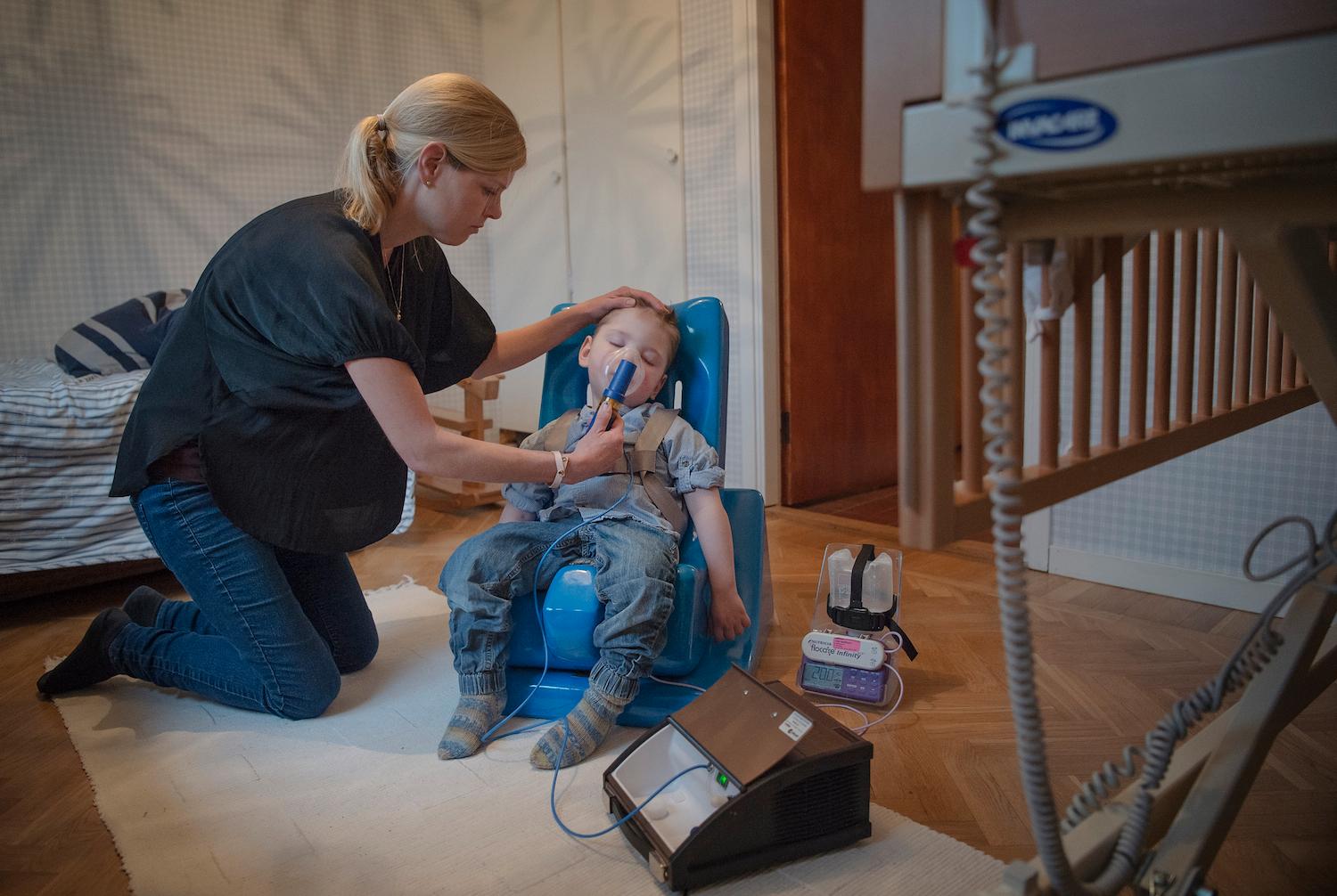 "Olof, 2, måste övervakas varje minut. Han har en mycket svår epilepsi som han kan dö av. Här inhalerar han luftrörsvidgande medicin med hjälp av sin mamma Karolina Hermansson.