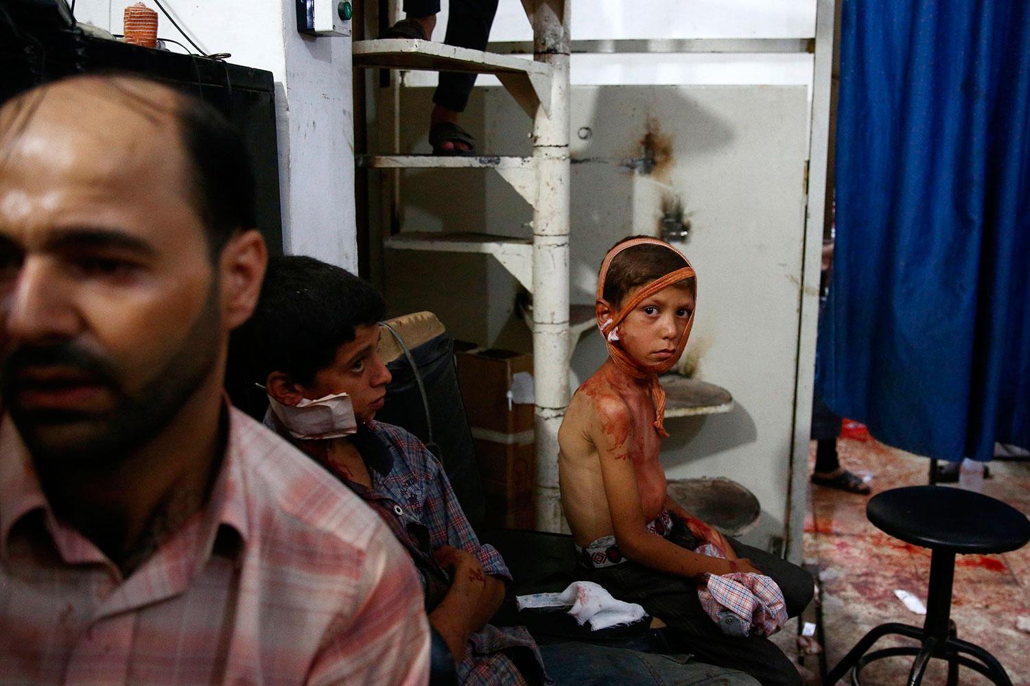 Två pojkar väntar på att få vård i ett provisoriskt sjukhus efter terrorbombningen mot marknaden.