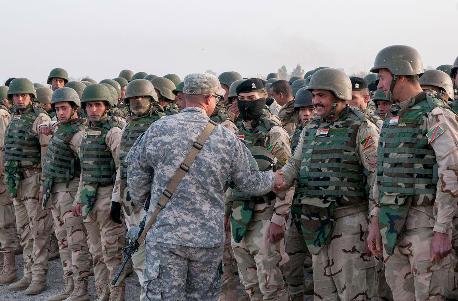 En amerikansk officer hälsar på irakiska soldater.