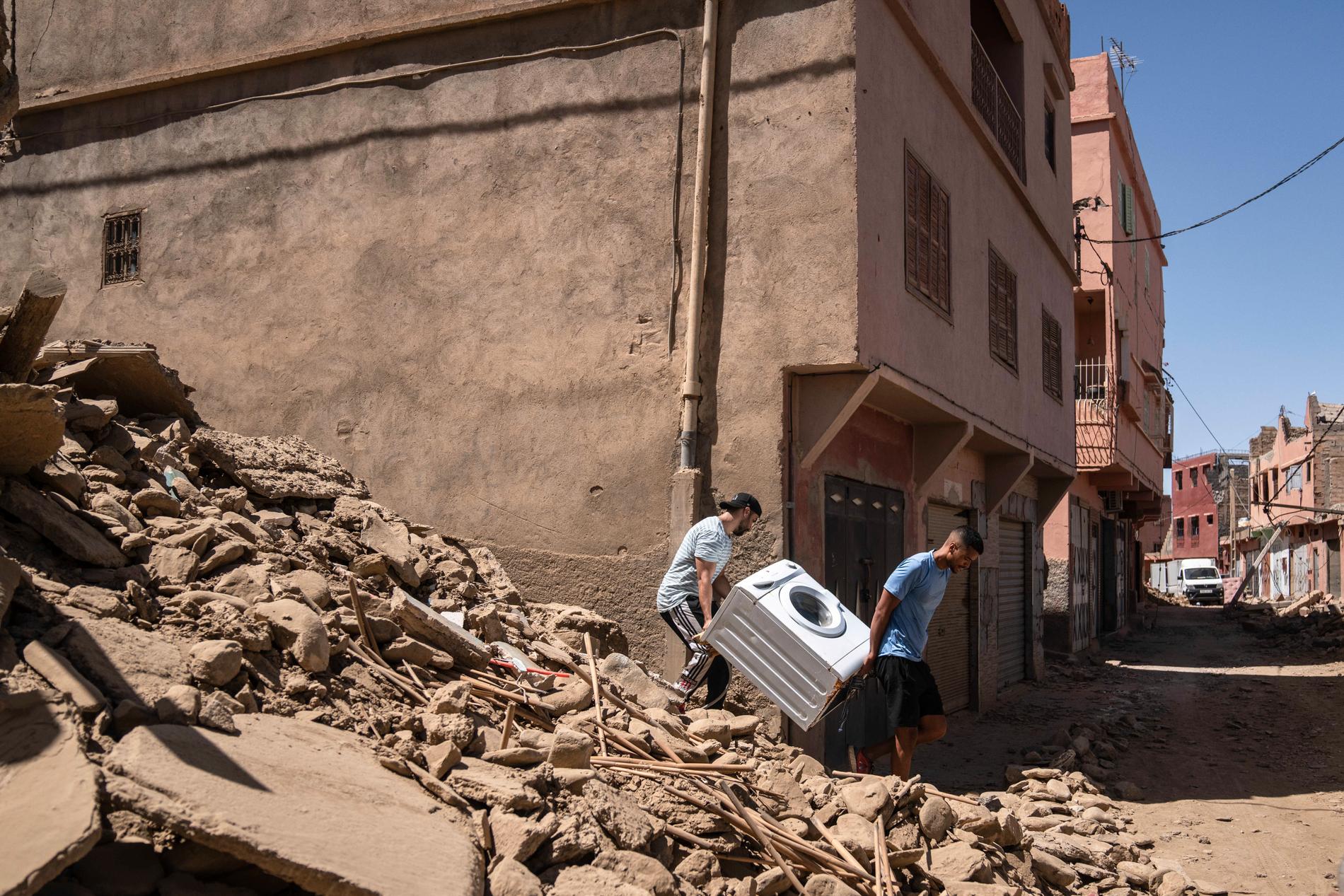 Män bär ut deras tvättmaskin från stenhögen som tidigare var deras hus i staden Amizmiz i närheten av Marrakech.