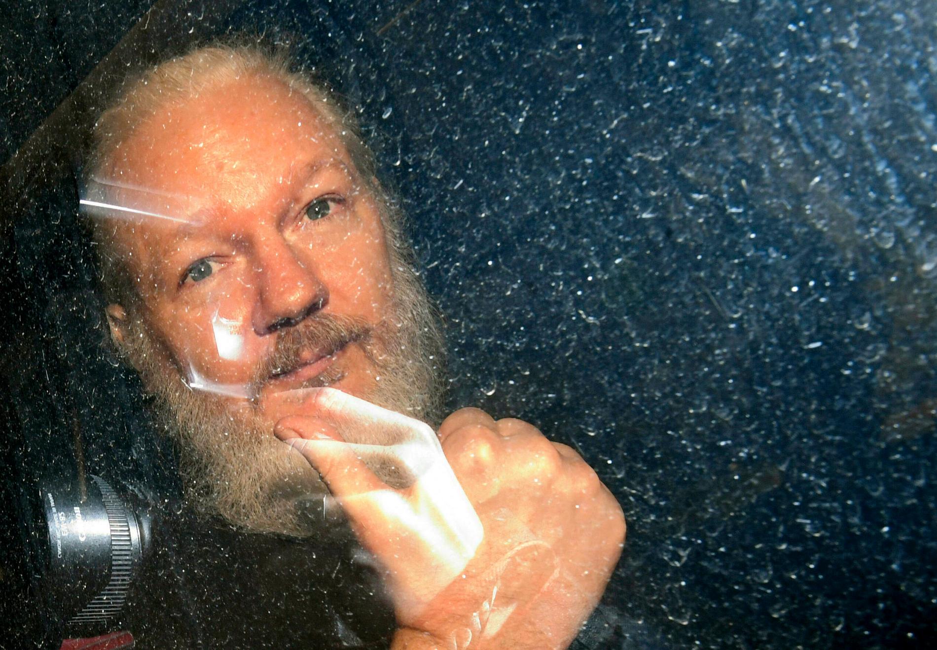 Assange förs iväg av polis.