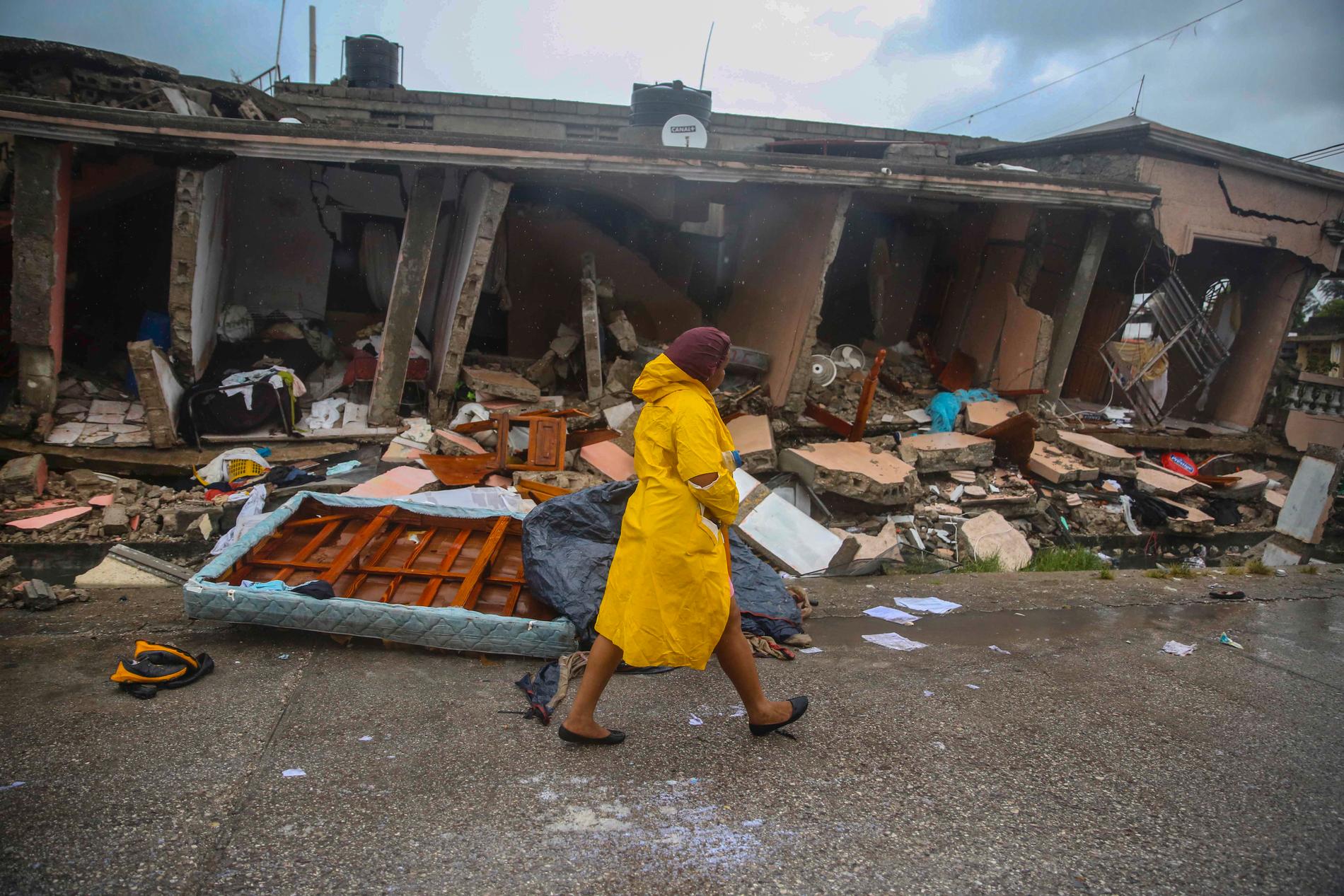 En kvinna går i ett totalförstört bostadsområde efter att det tropiska ovädret Grace dragit in, bara några dagar efter jordbävningen.