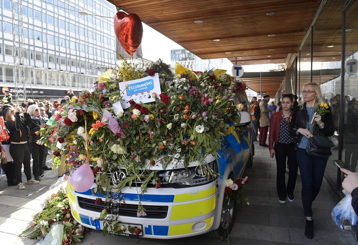 Blomsterhav över en polisbil vid Sergels torg på söndagen.