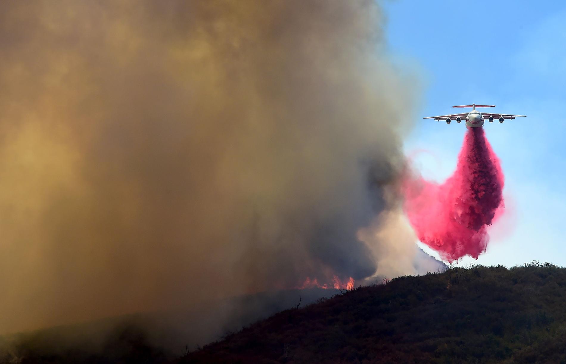 En helikopter släpper brandskyddsmedel över bergen vid Placerita Canyon Road i Kalifornien.