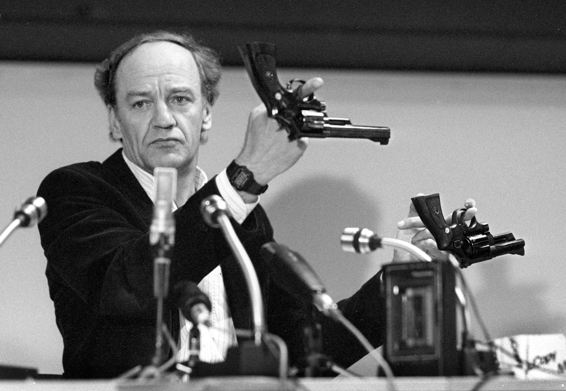 Hans Holmér ledde utredningen mellan 1986–87. På bilden håller han upp två revolvrar av märket Smith & Wesson 357 Magnum under en presskonferens på polishuset i Stockholm 31:a mars 1986.